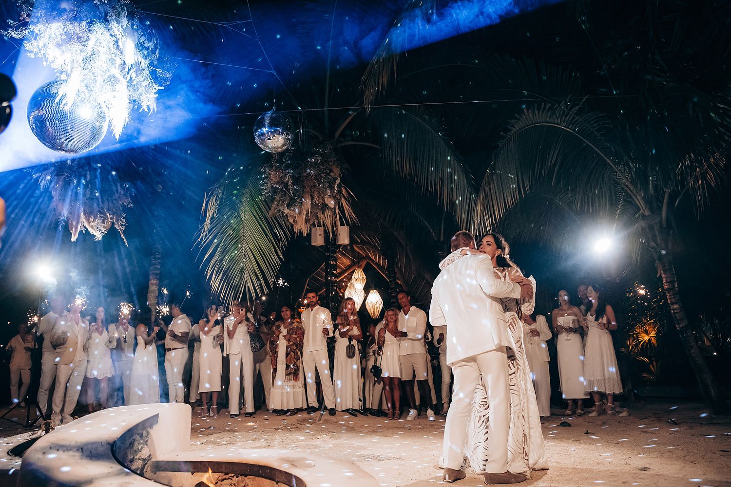 Night beach celebration with blue lighting and sparklers creating a magical atmosphere.