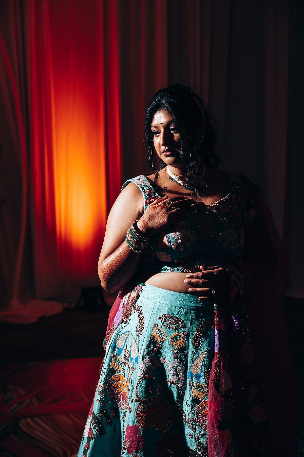 Dramatic boudoir photography series with red lighting and floral print skirt.