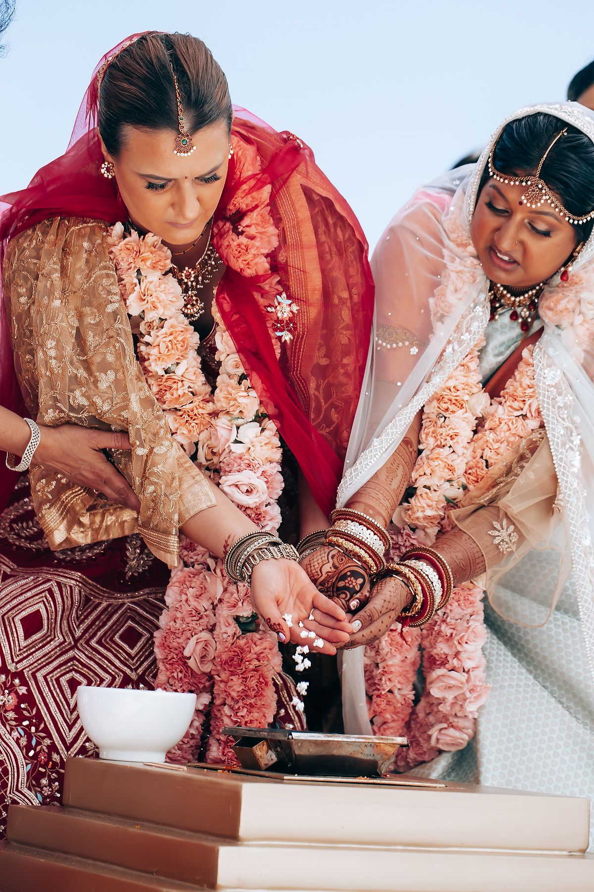 Close-up of traditional Indian wedding ceremony rituals with coral and red attire details.
