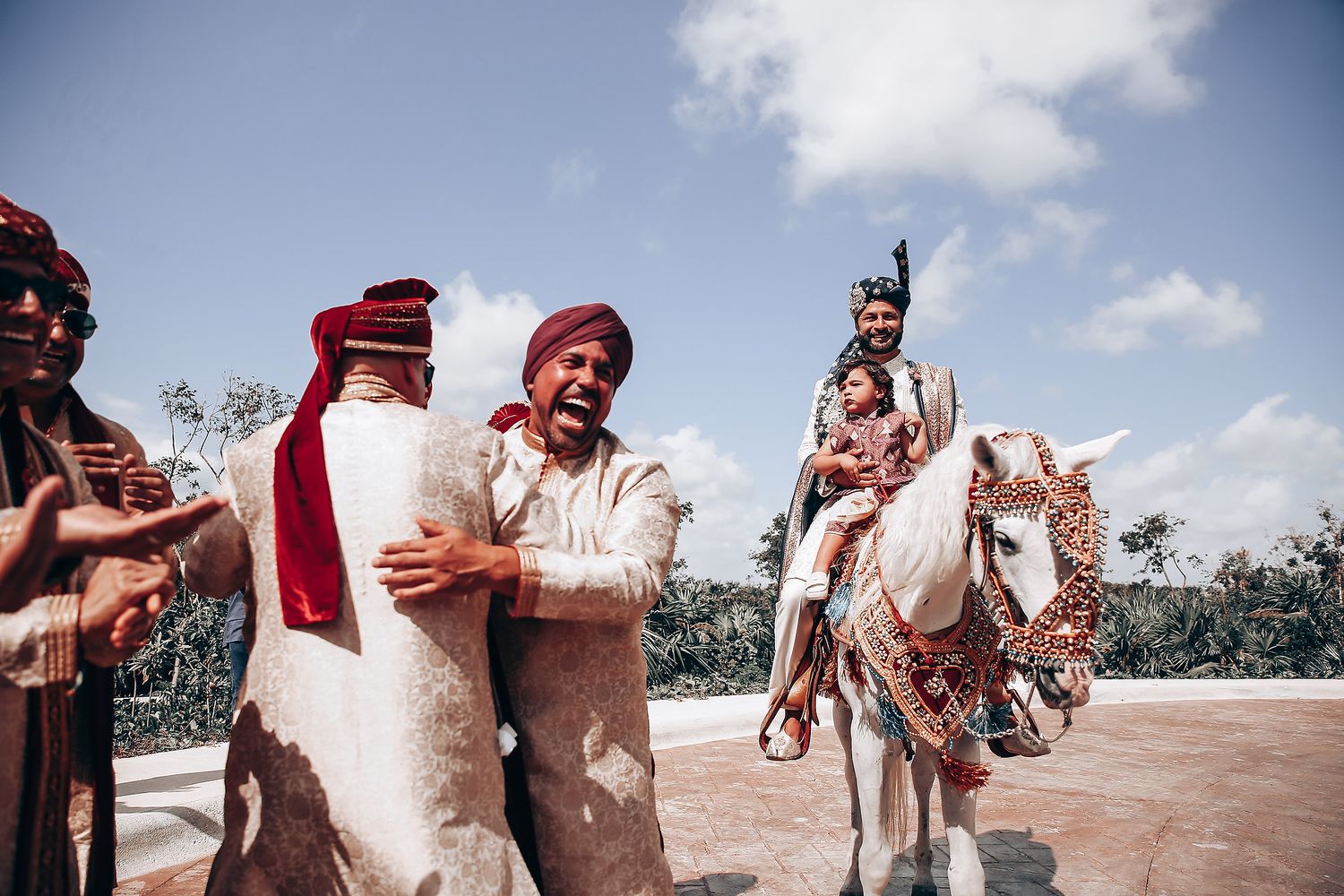 Wedding celebration with traditional attire and decorated white horse outdoors.