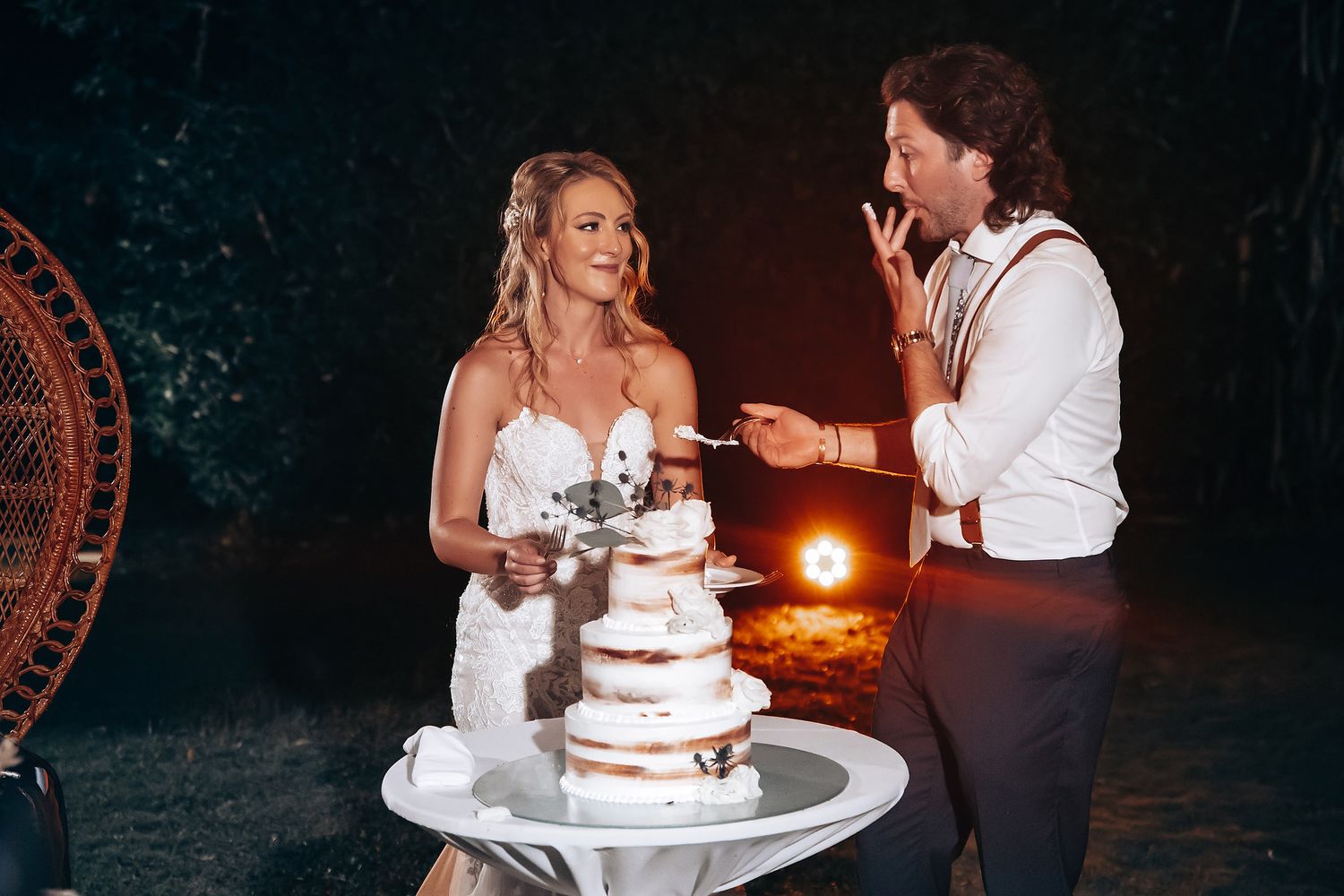 Couple cutting their wedding cake together during an intimate nighttime reception celebration.
