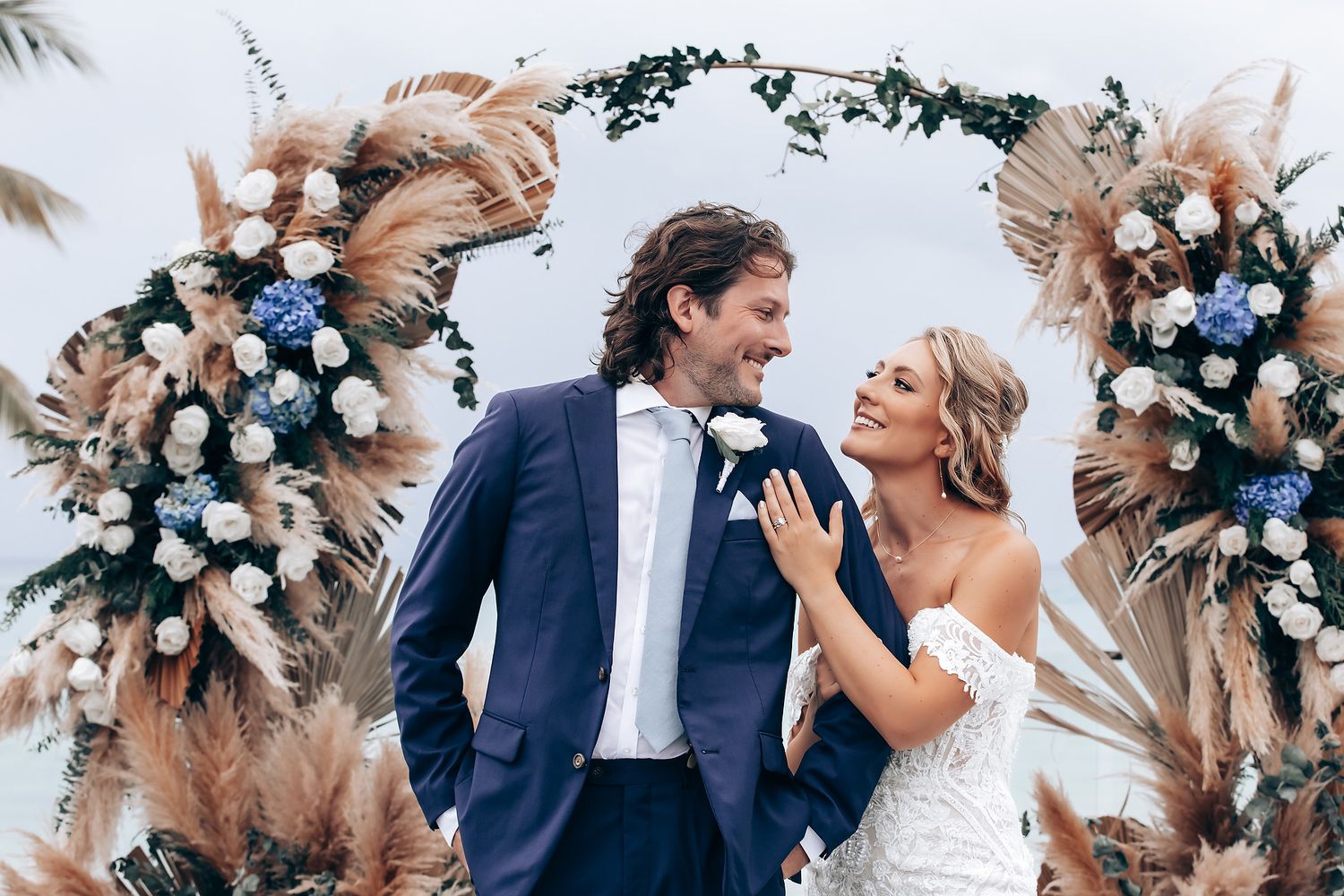 Romantic beach wedding scene with pampas grass and floral decorations.
