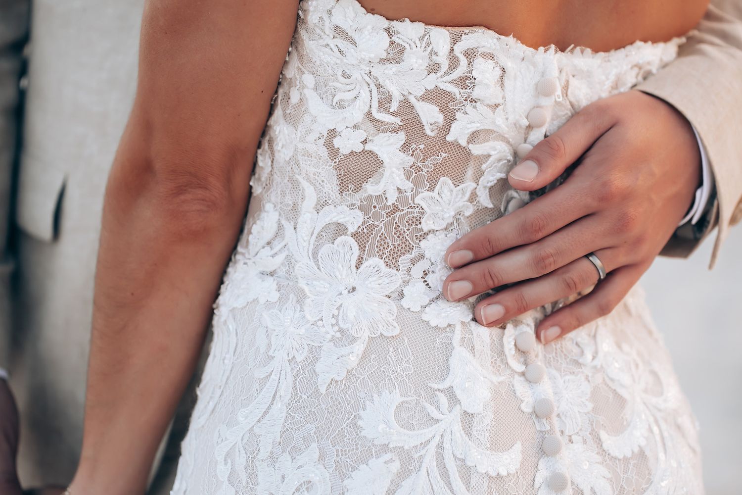 Close-up detail of intricate lace pattern on a white wedding dress.