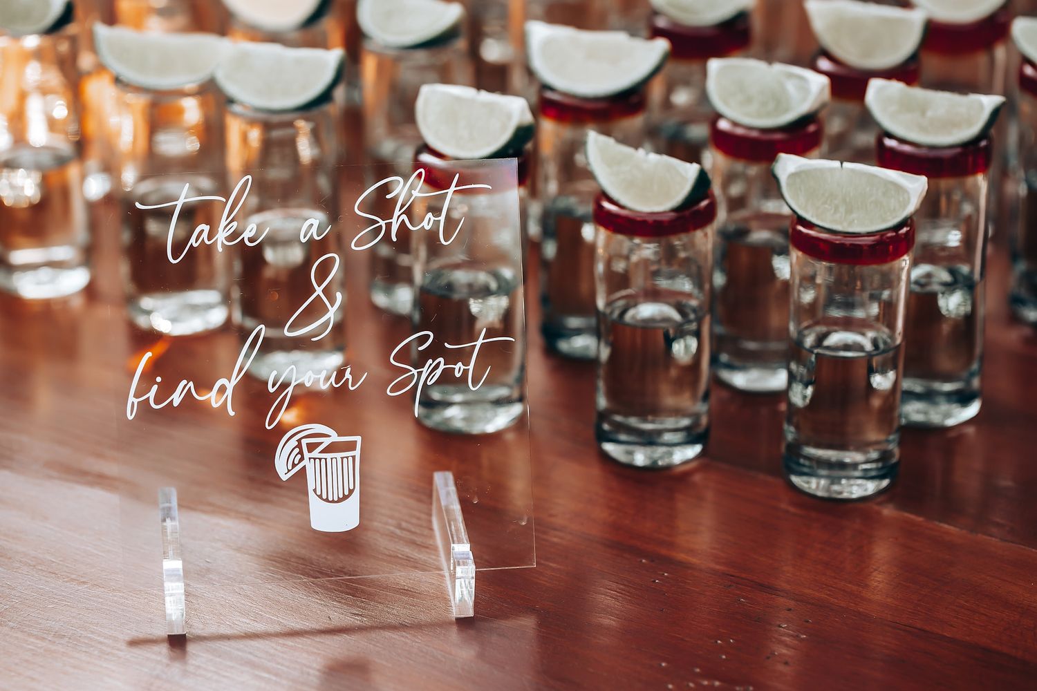 Wedding reception detail showing shot glasses with a decorative 'take a shot' sign on display.