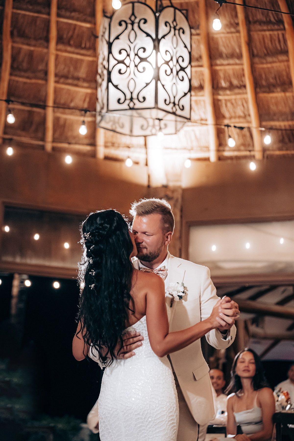 First dance under thatched roof palapa with romantic string lighting.