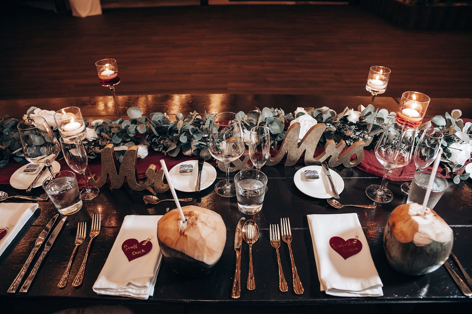 Elegant wedding reception table settings with glowing candles and rustic decor in a dark, intimate atmosphere.