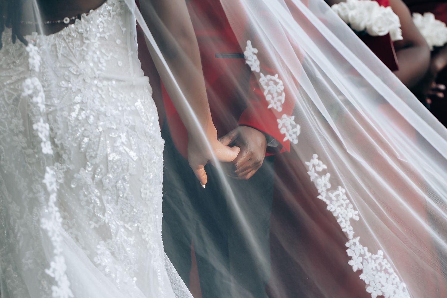 Close-up details of a white lace wedding dress with delicate embroidery and beading patterns.
