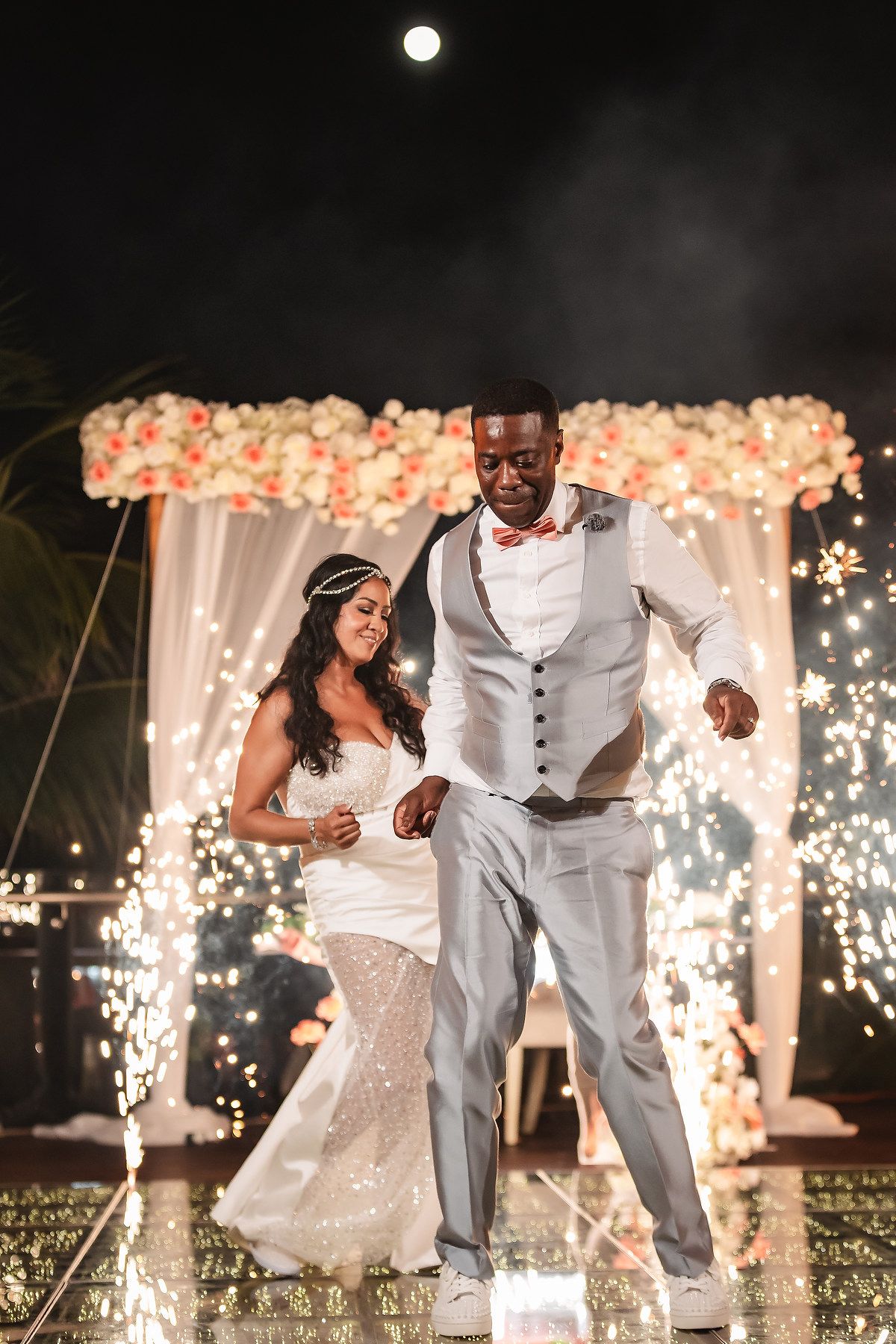 Couple dancing together during their wedding reception with sparklers and twinkle lights creating a romantic ambiance.