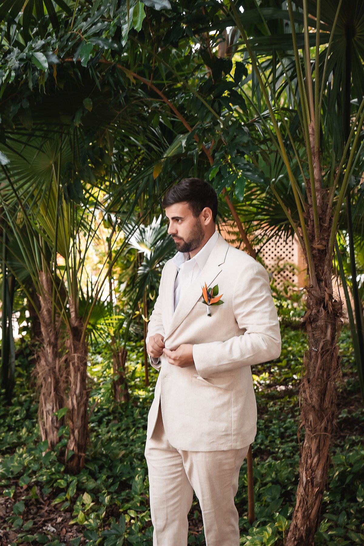 Wedding attire detail in cream colored suit against tropical garden backdrop.