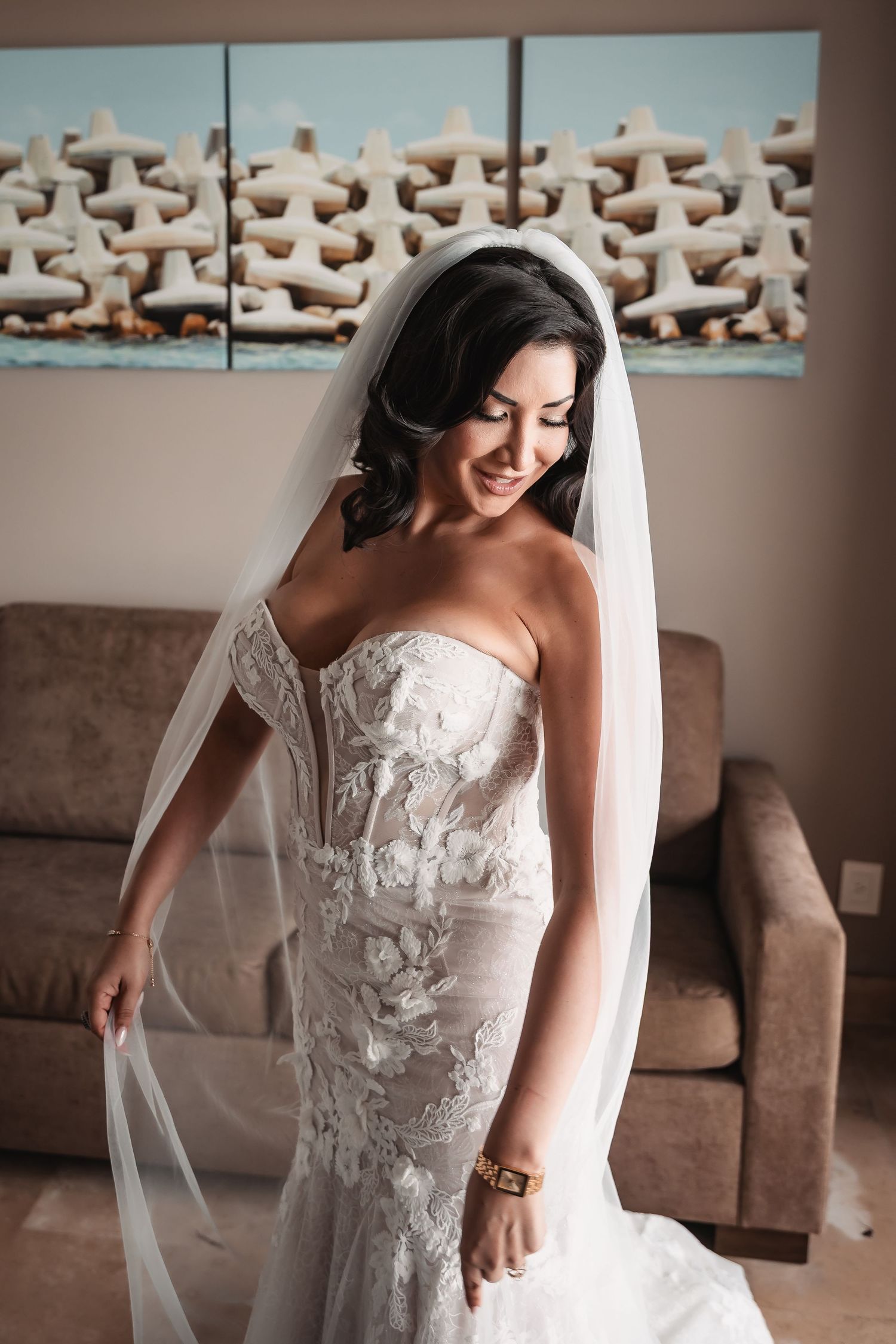 A strapless lace wedding gown with delicate veil details photographed in an indoor setting.
