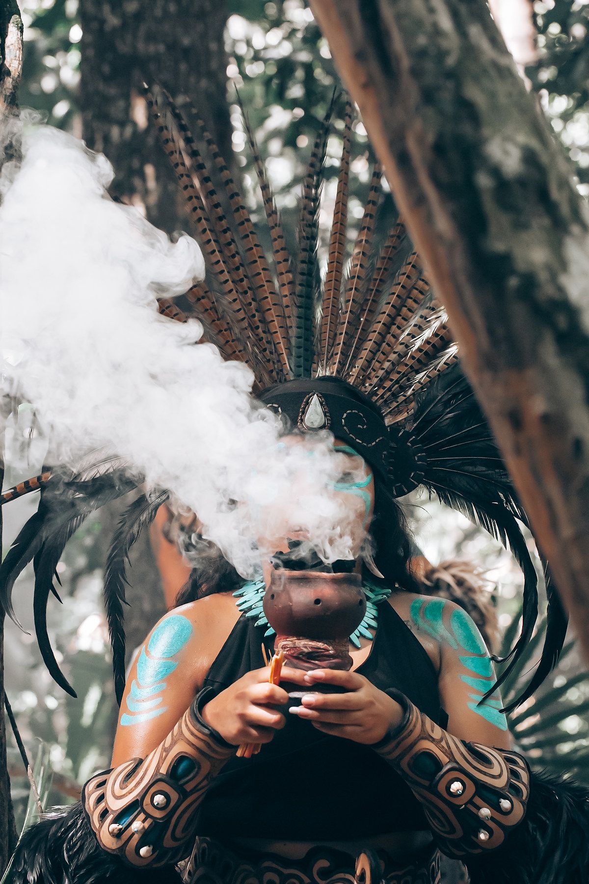Dramatic photo of a traditional feathered headdress against a misty forest backdrop with smoke effects.