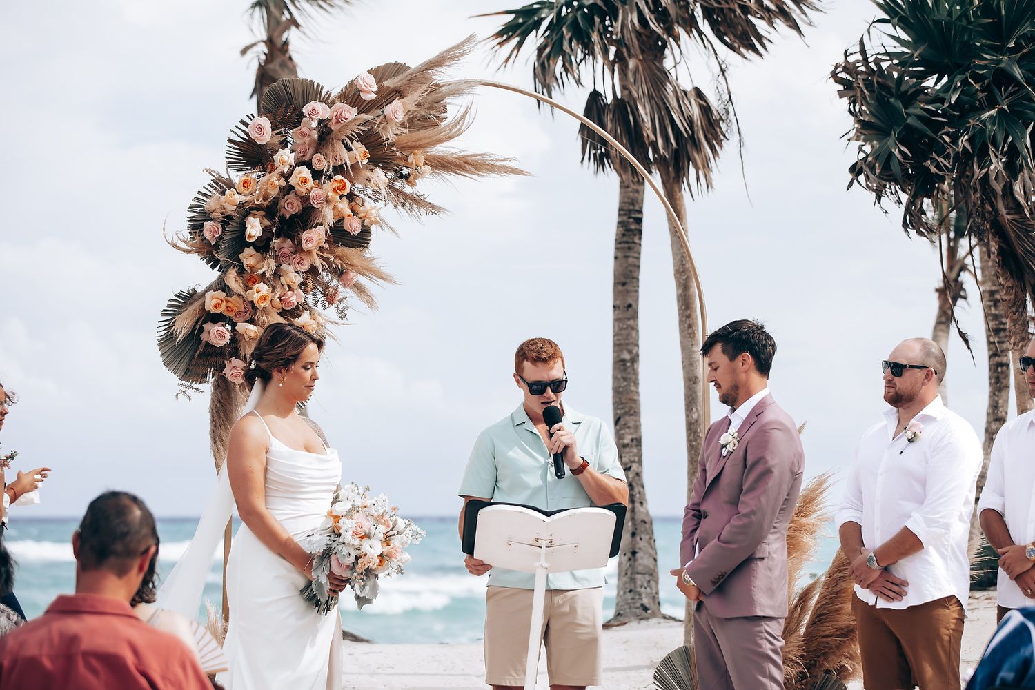 Beach wedding ceremony with palm trees swaying in the ocean breeze.