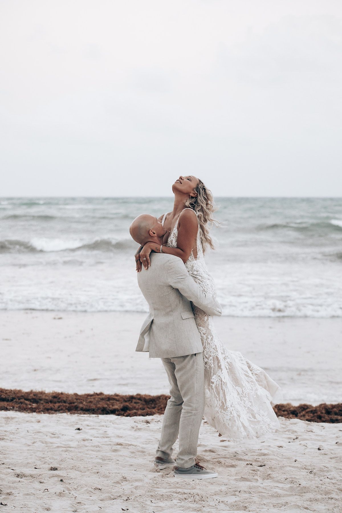 A romantic embrace on a sandy beach with ocean waves in the background.