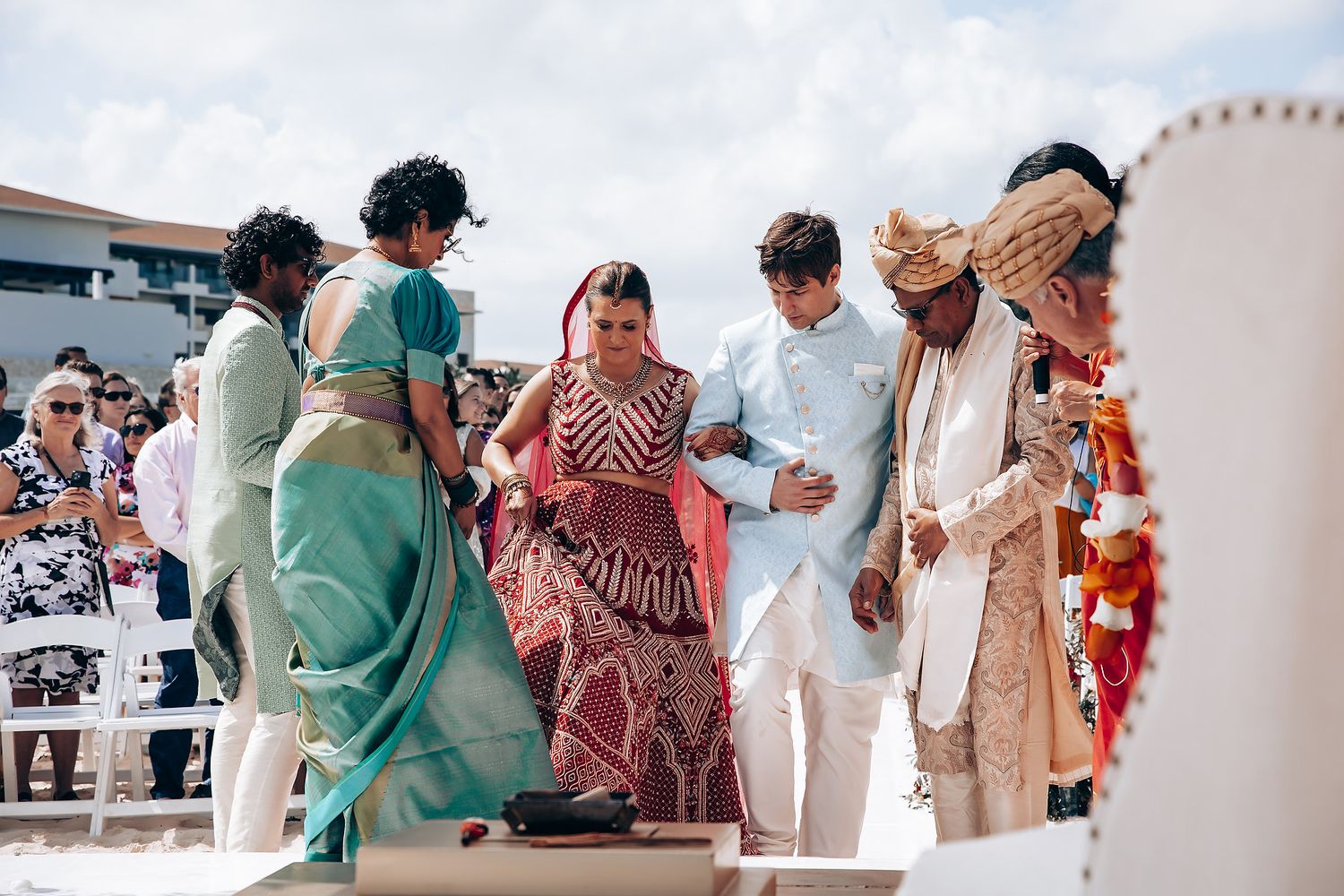 Wedding guests gather outdoors in traditional attire with mint green and burgundy color scheme.