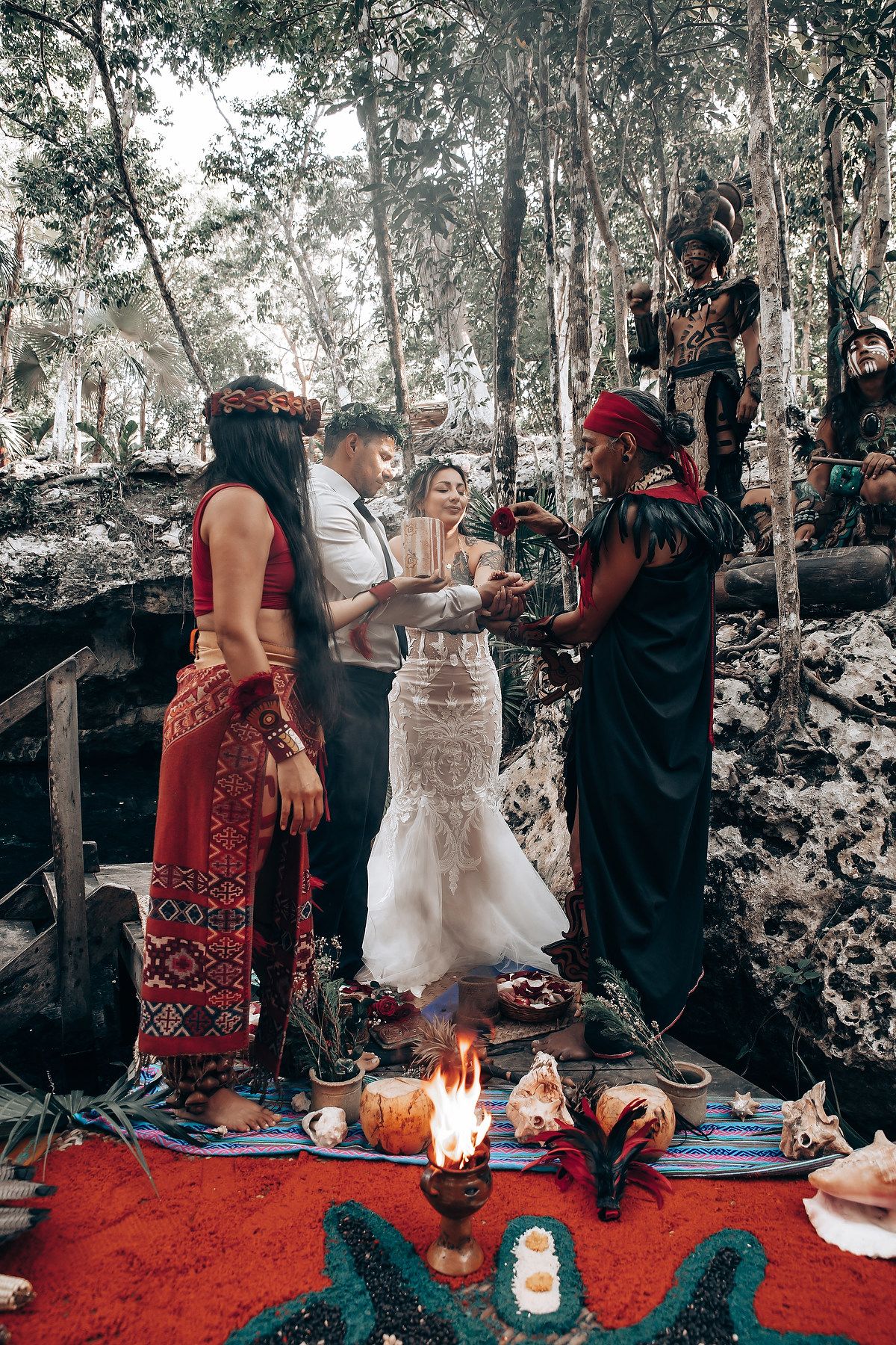 A forest wedding ceremony featuring red decor, candles, and mystical elements on display.
