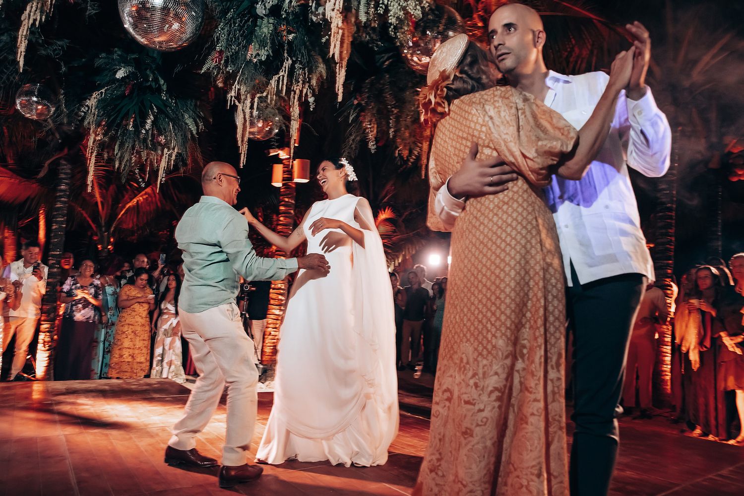 Wedding guests dancing on an outdoor dance floor at night.