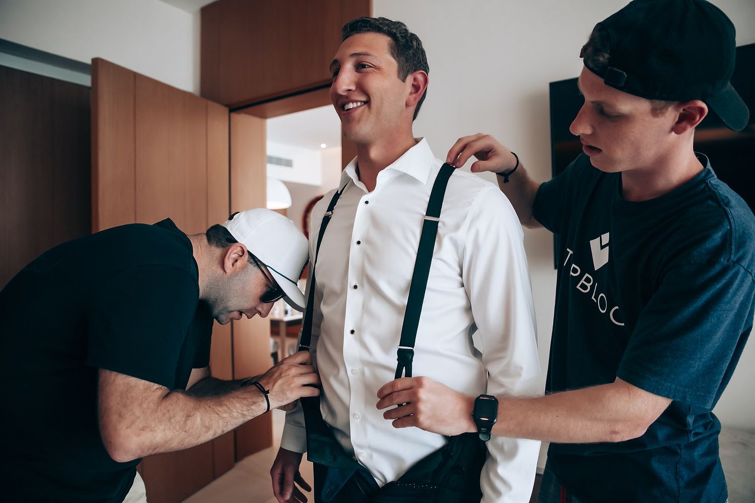 Candid moments of groomsmen helping with wedding preparations.