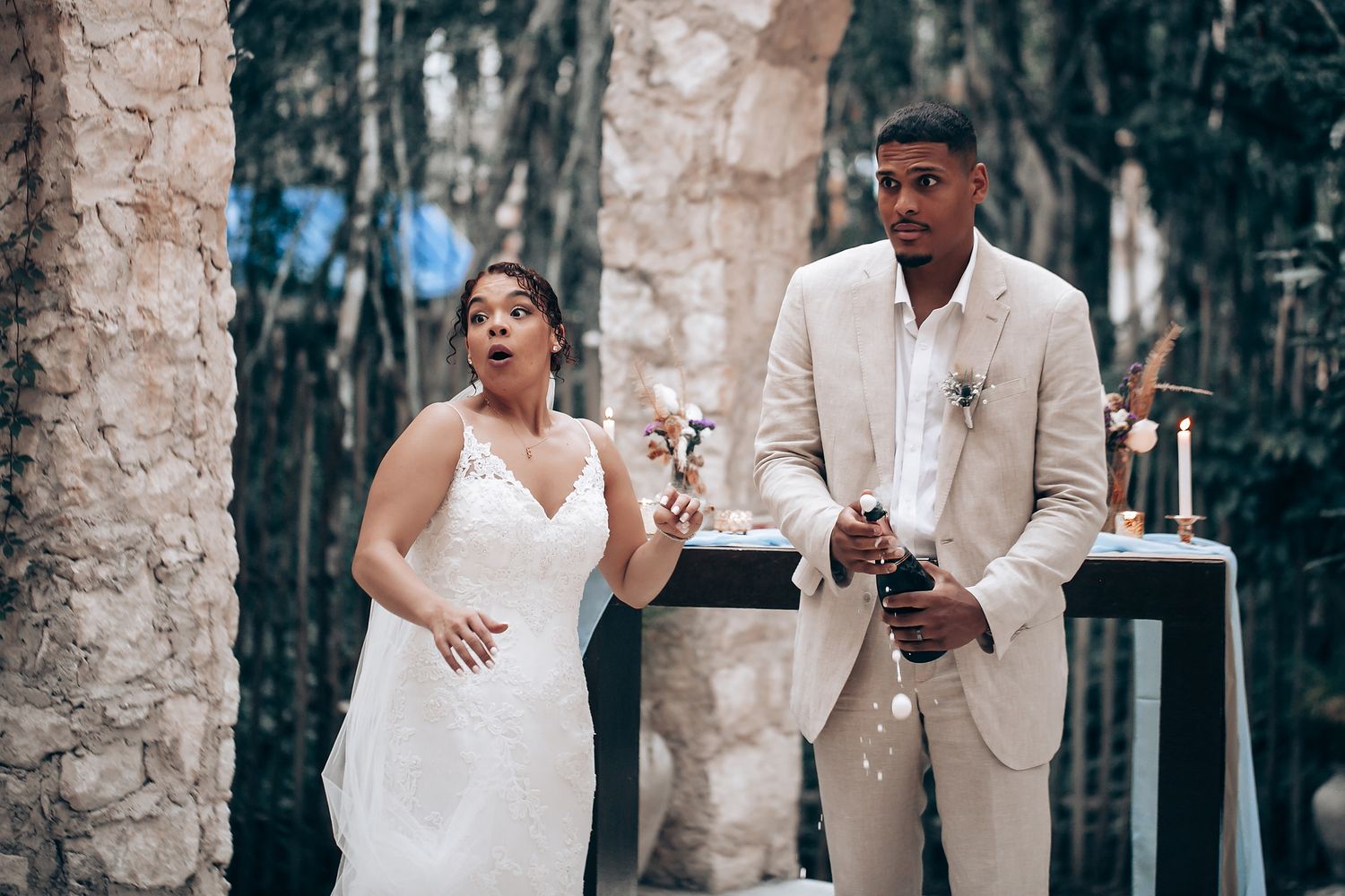 A couple in white and beige wedding attire embracing during an outdoor photo session.