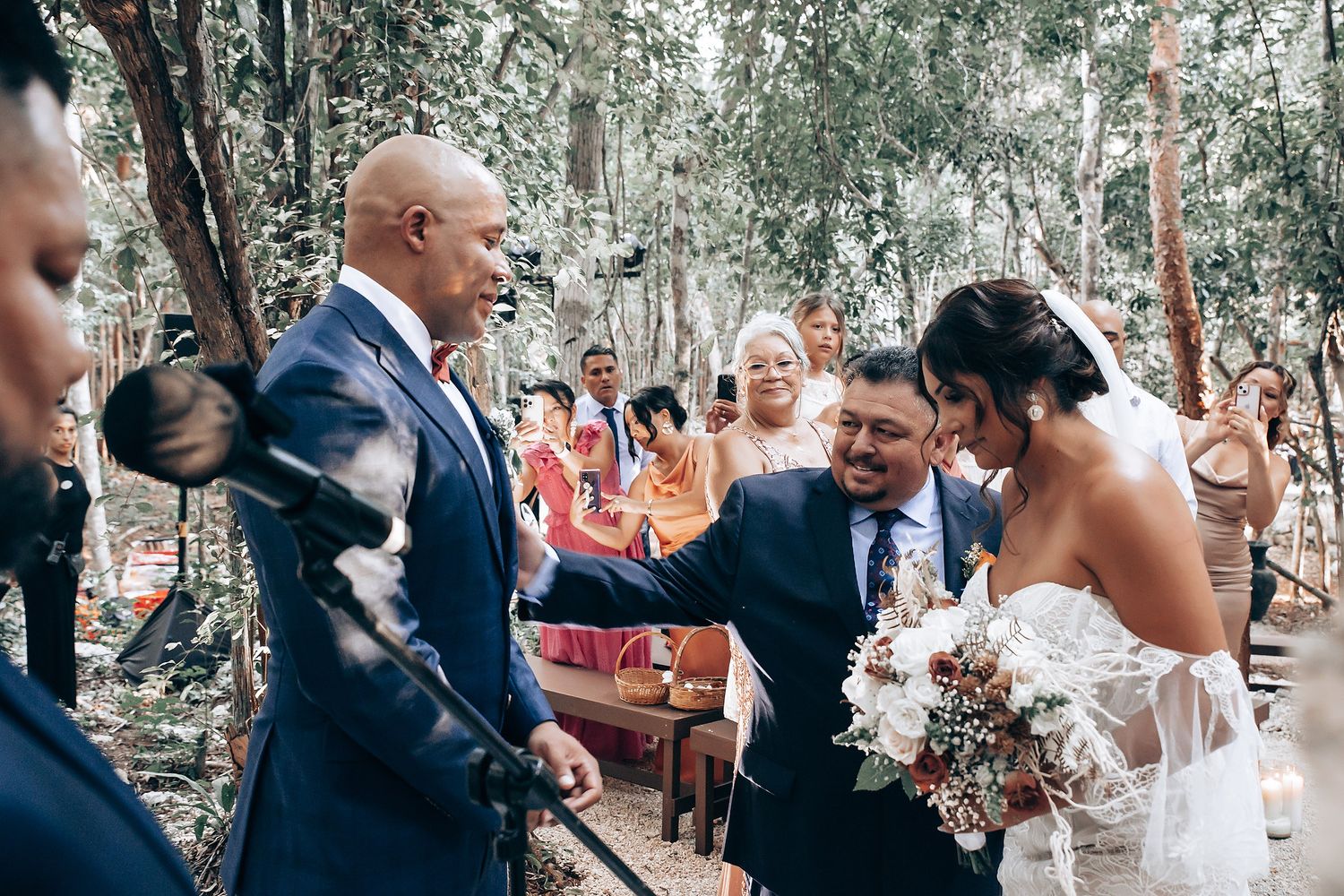 Joyful wedding celebration moment in an outdoor forest setting with guests looking on.