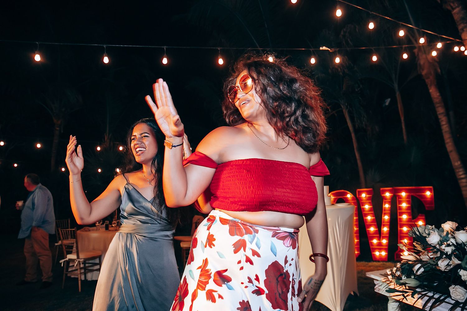 Wedding reception guests dancing under string lights at outdoor evening celebration.