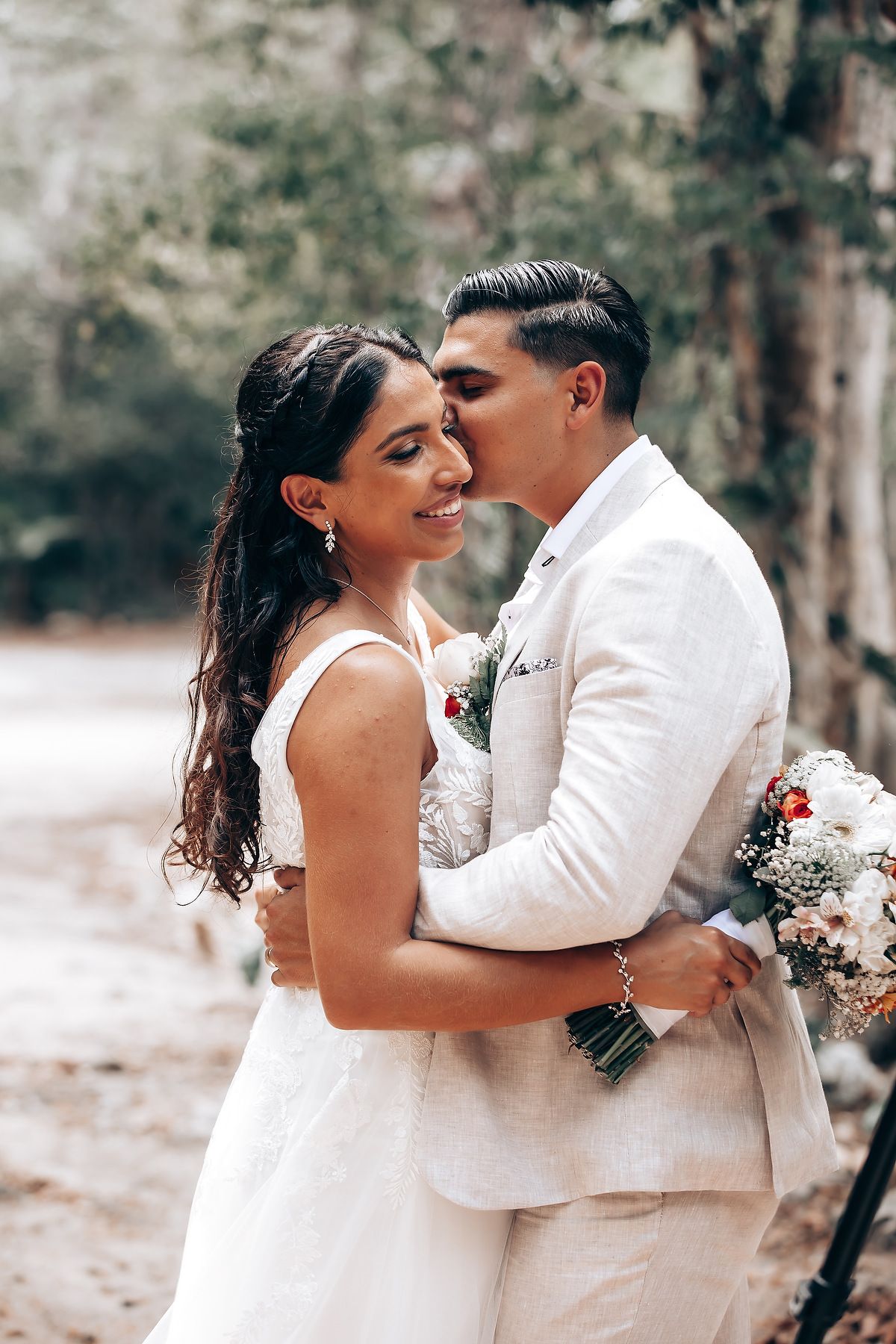 A romantic wedding couple embraces during their forest photo session.