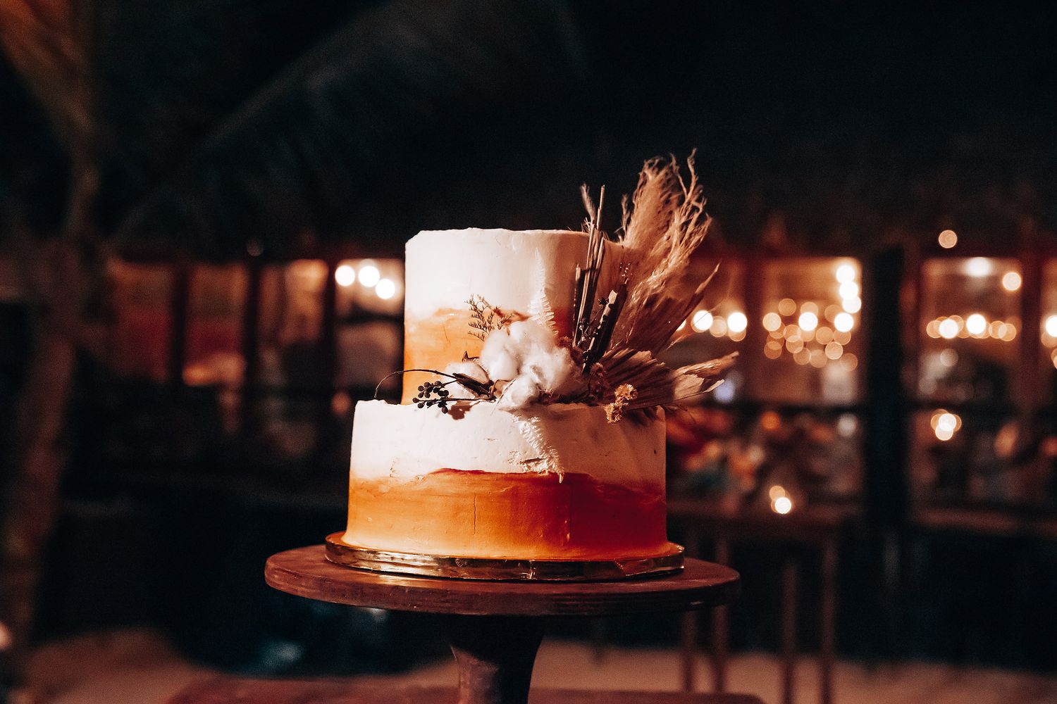 Wedding cake display with ambient lighting and string lights creating a warm atmosphere.