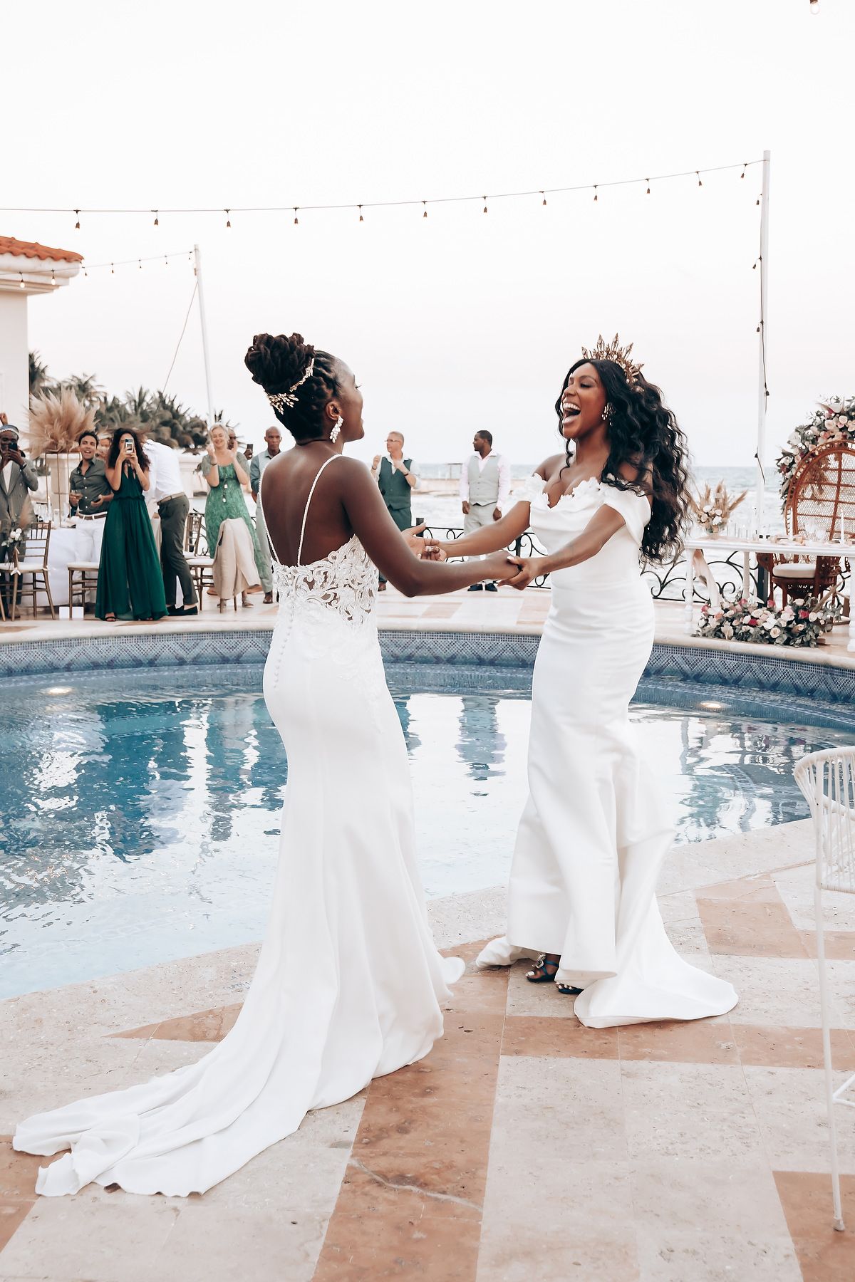 Wedding celebration by a poolside with white gowns flowing in the evening light.