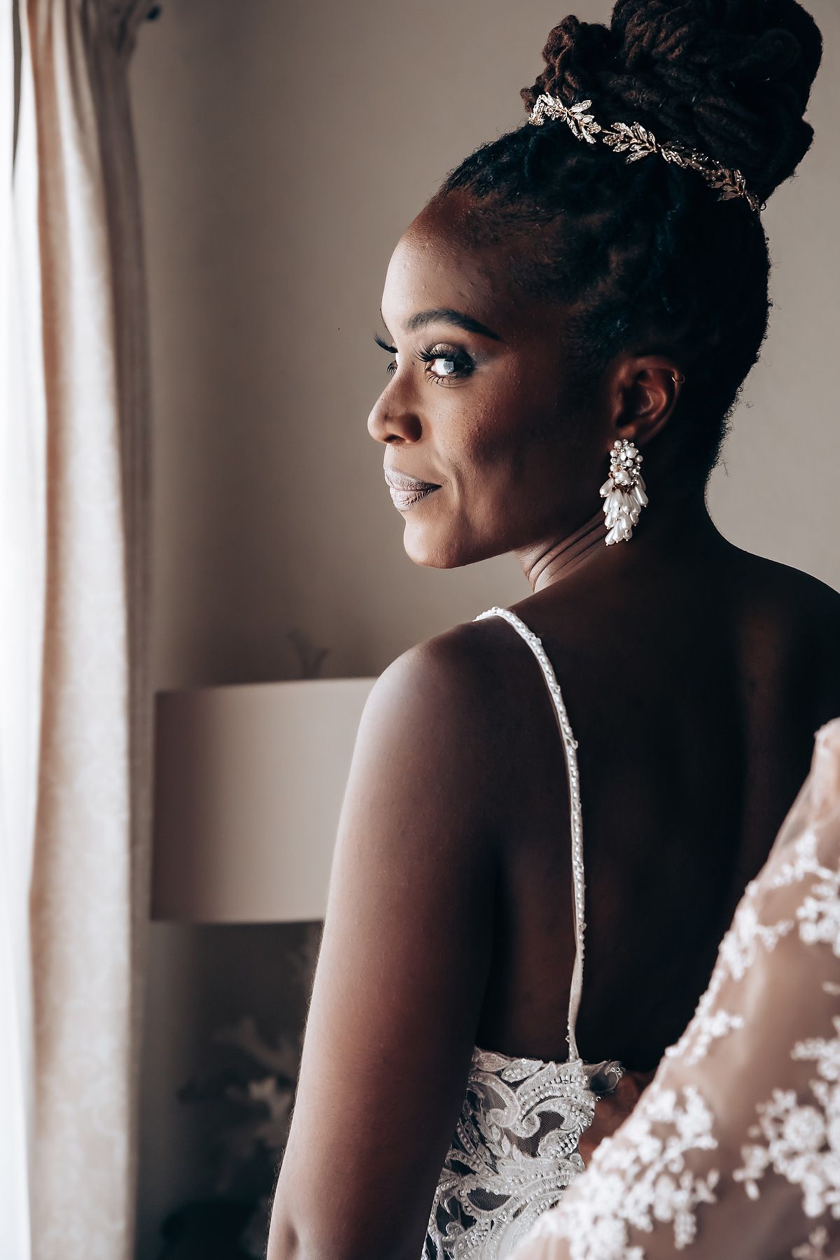 Elegant bridal portrait with delicate lace details and sparkling headpiece in soft natural lighting.