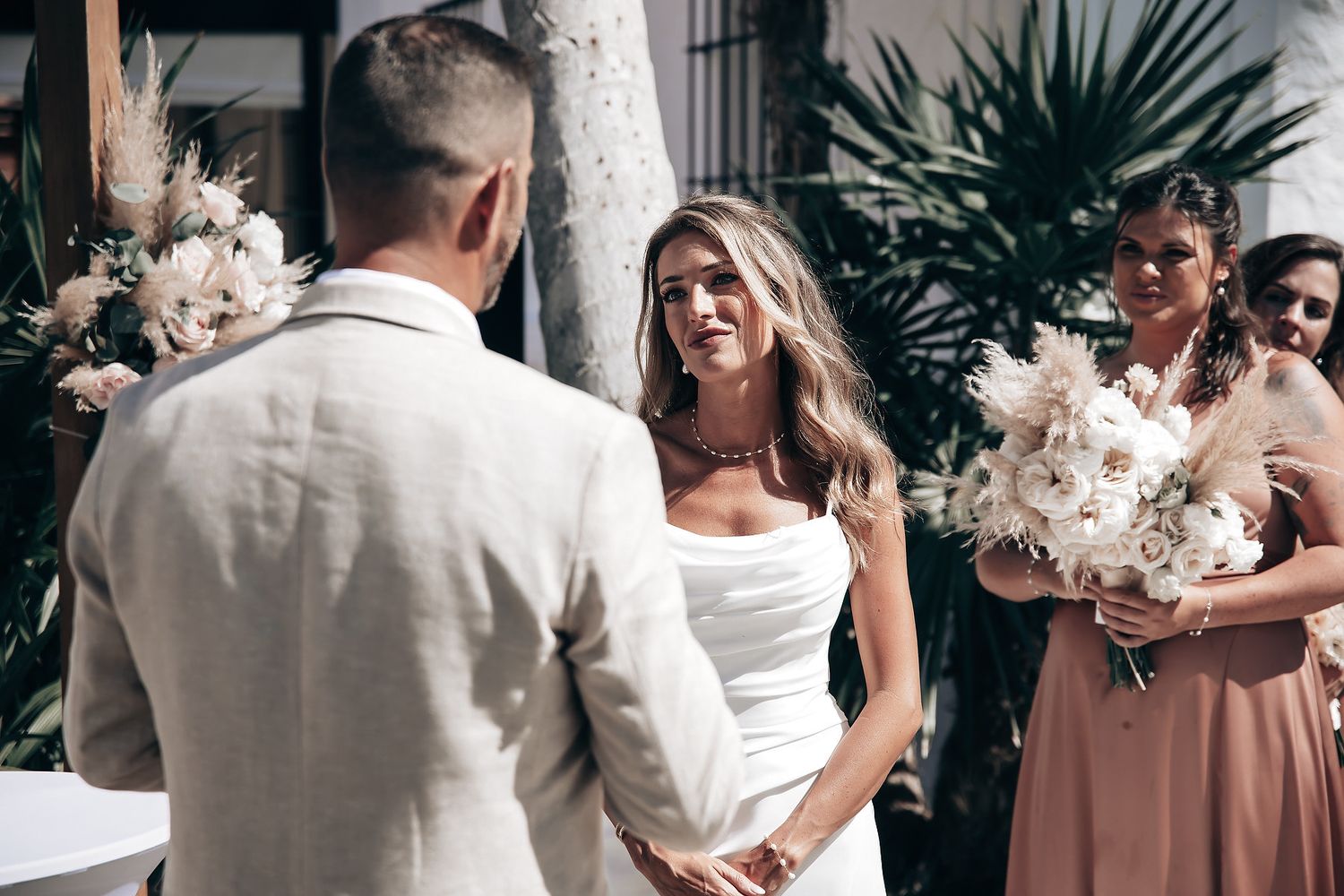 A bride and groom embrace at their outdoor wedding ceremony surrounded by guests.