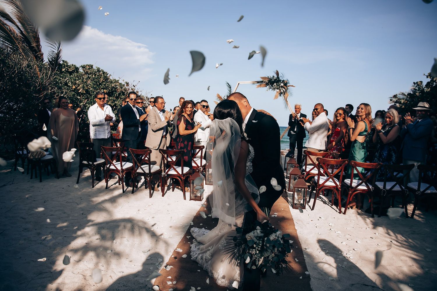 Guests celebrating with bubbles during an outdoor beach wedding ceremony.