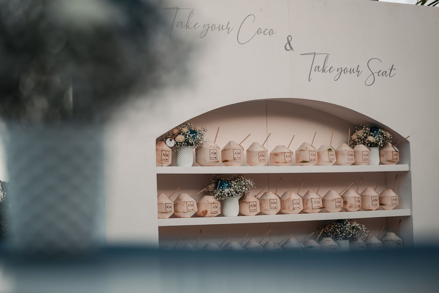 Elegant wedding seating chart display with small house-shaped cards on white shelving unit.
