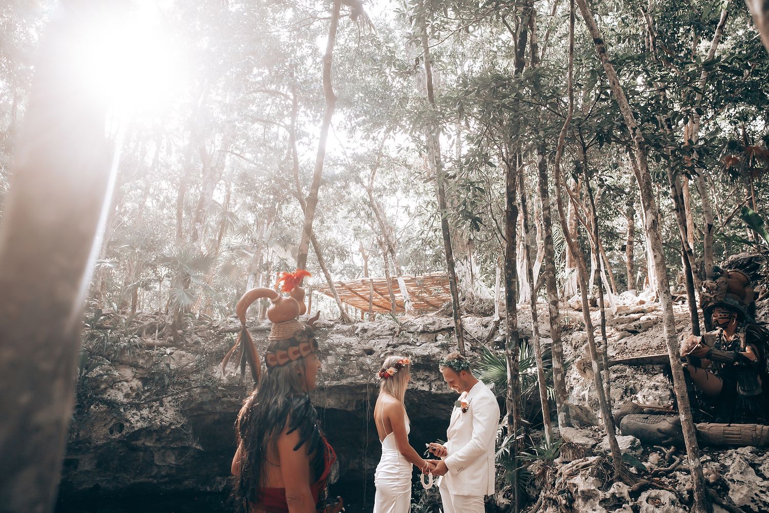 Guests enjoying a casual outdoor celebration in a sunlit forest setting.