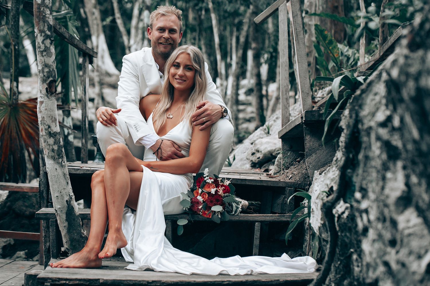 An intimate wedding photoshoot on a rustic wooden platform surrounded by trees.