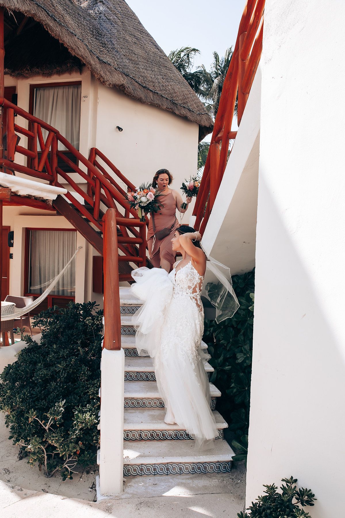 White wedding dress flowing on outdoor staircase with tropical landscaping.