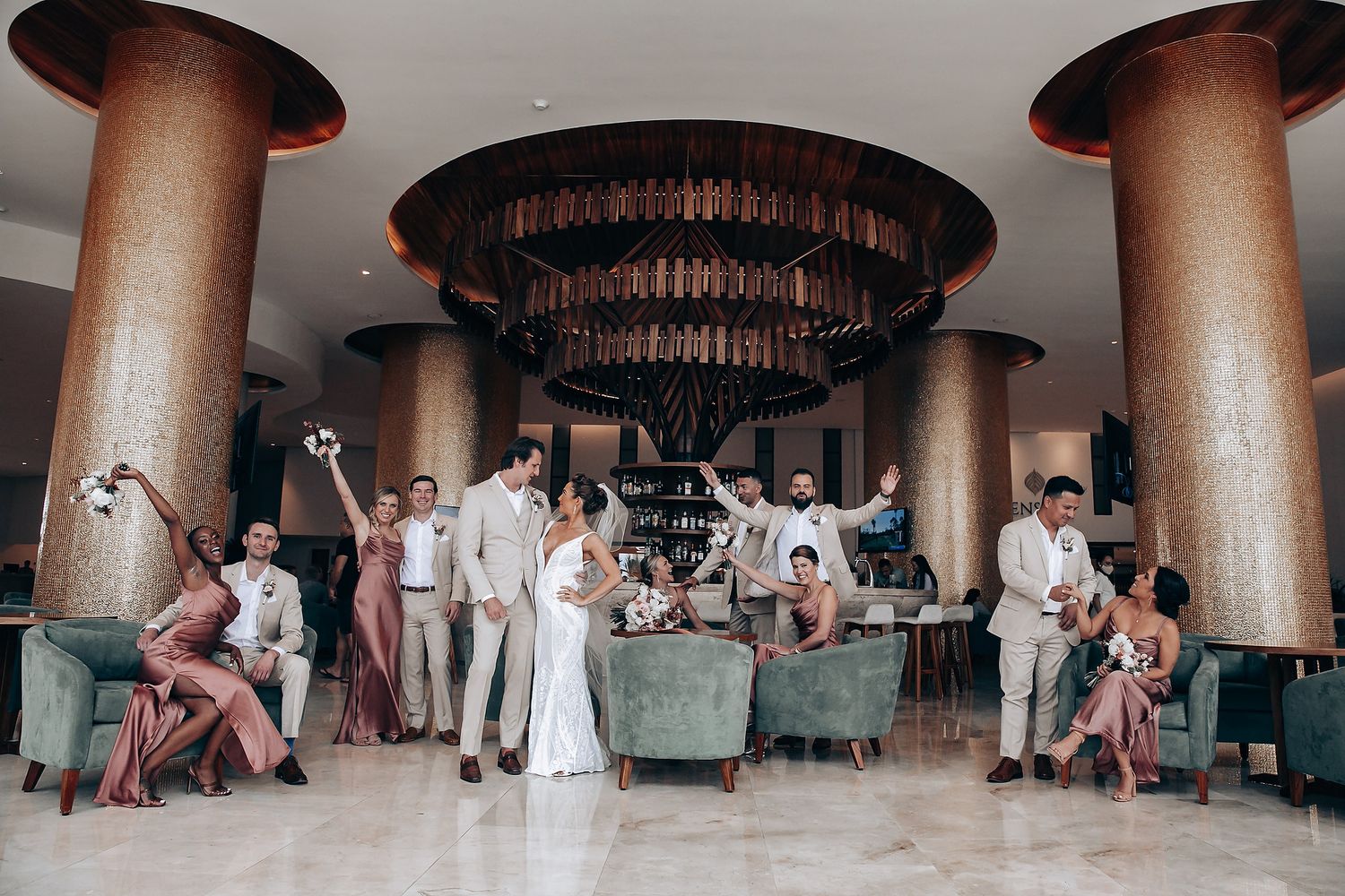 Wedding guests gather in an elegant columned venue with marble floors and circular seating arrangement.