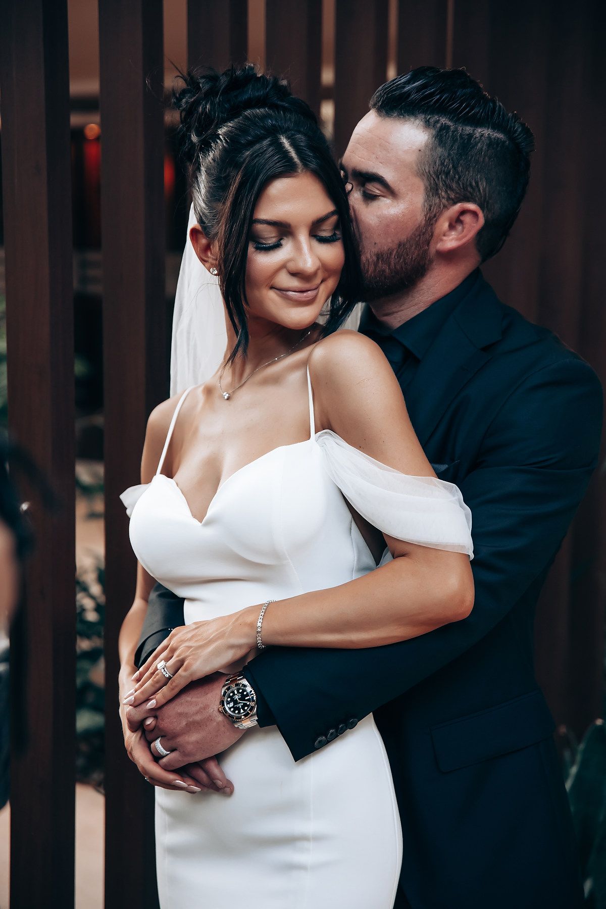 Intimate couple portraits against dark wooden backdrop in elegant wedding attire.