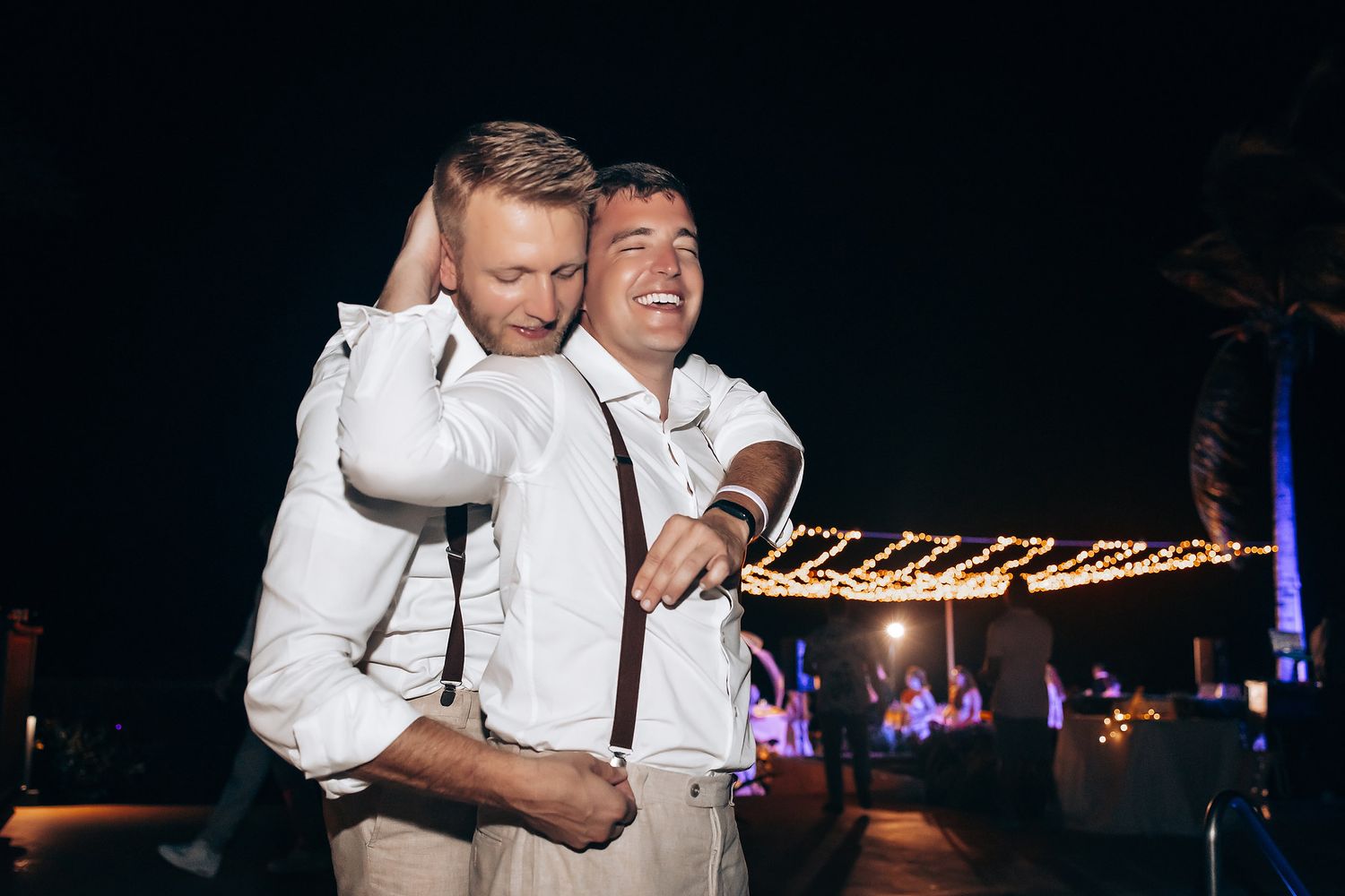 Nighttime wedding reception with string lights and dancing celebrations.