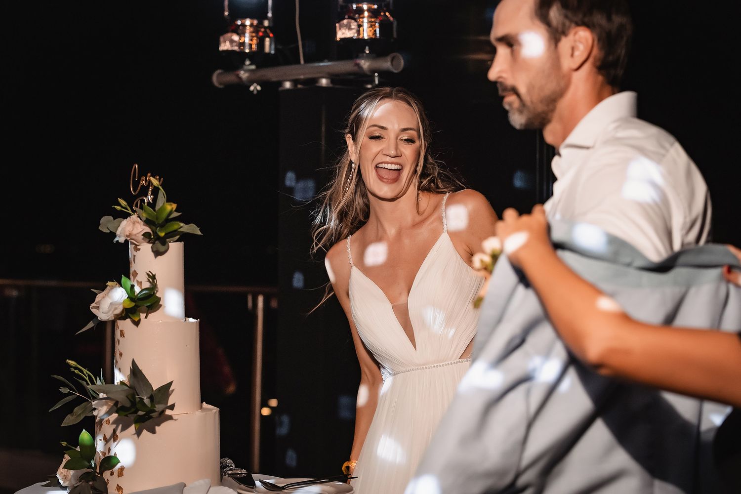 Joyful celebration during cake cutting ceremony at wedding reception.