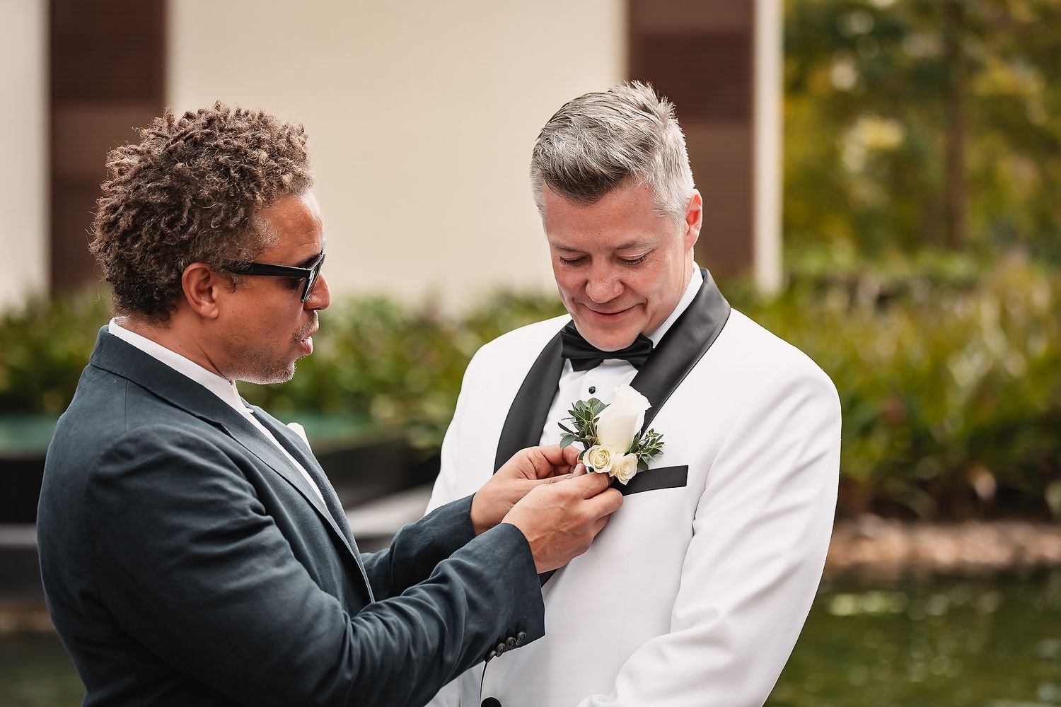 Groomsmen share emotional embraces and hugs during wedding preparations outdoors.