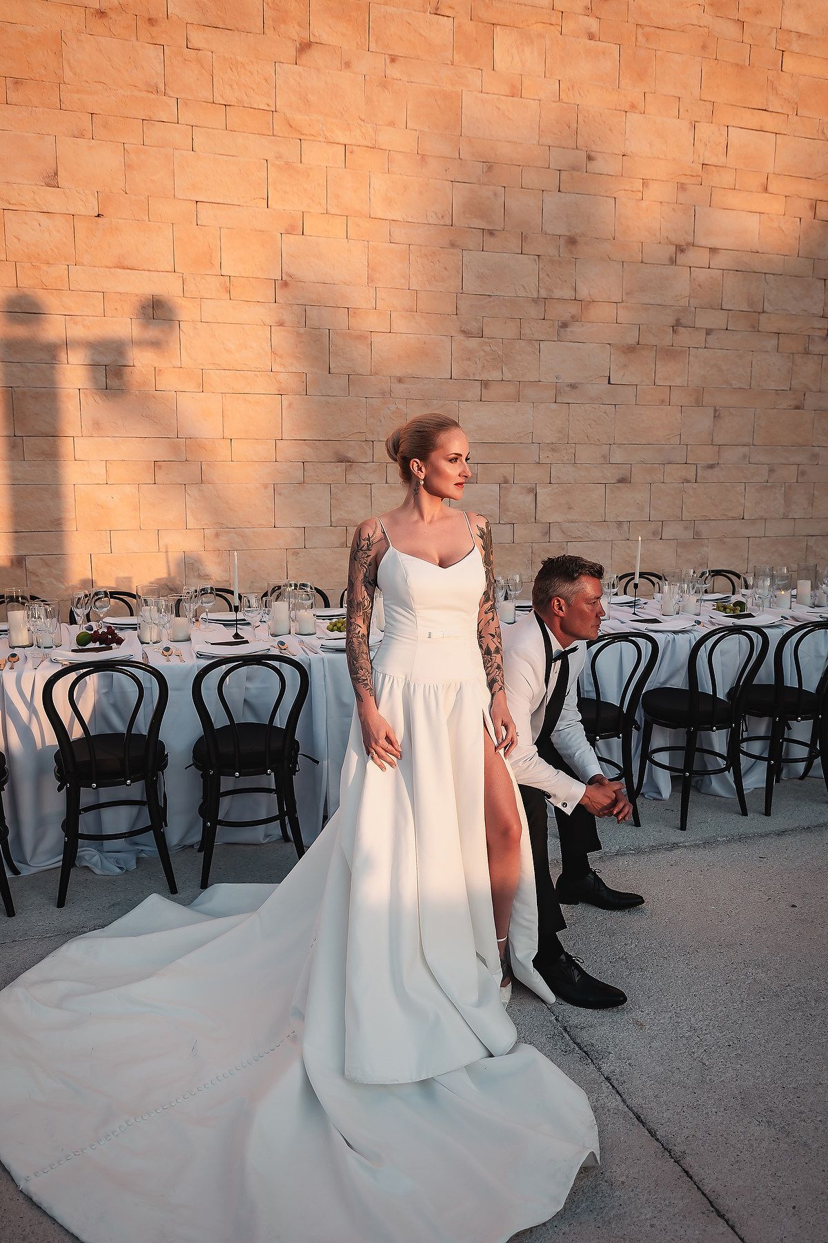 Elegant wedding photo session against a textured brick wall with warm lighting.