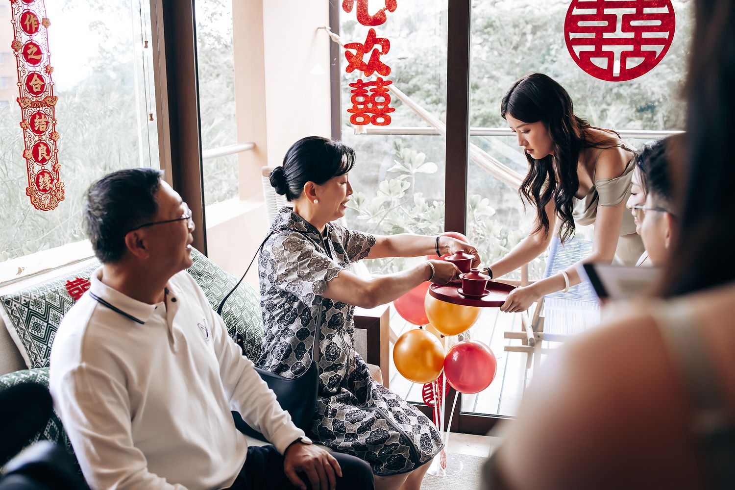 Traditional Chinese tea ceremony with guests gathered around a table with red decorations.