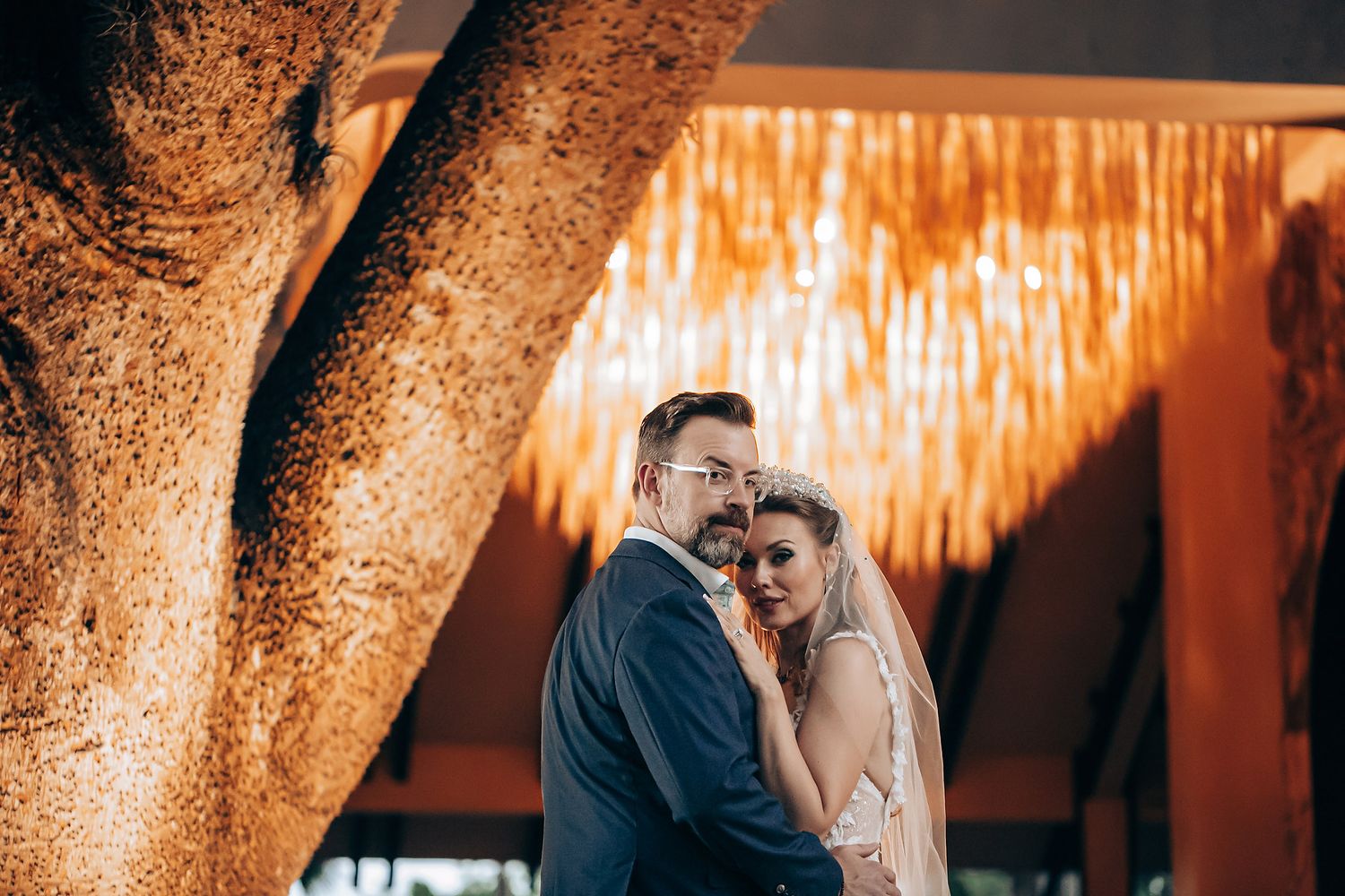 A couple shares an intimate moment under warm amber lighting during a romantic evening celebration.