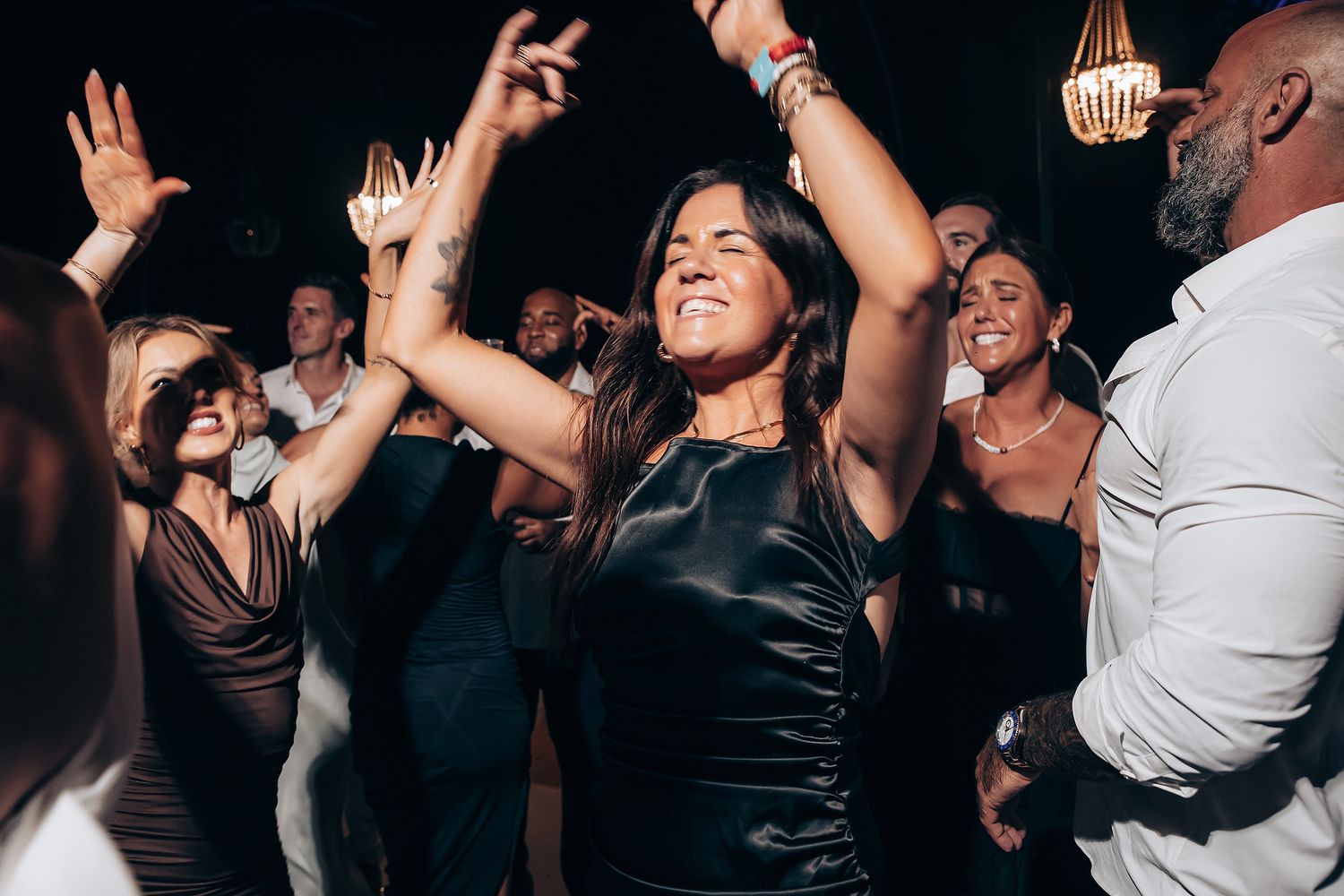 People dancing and raising their hands while enjoying themselves at a nightclub party.