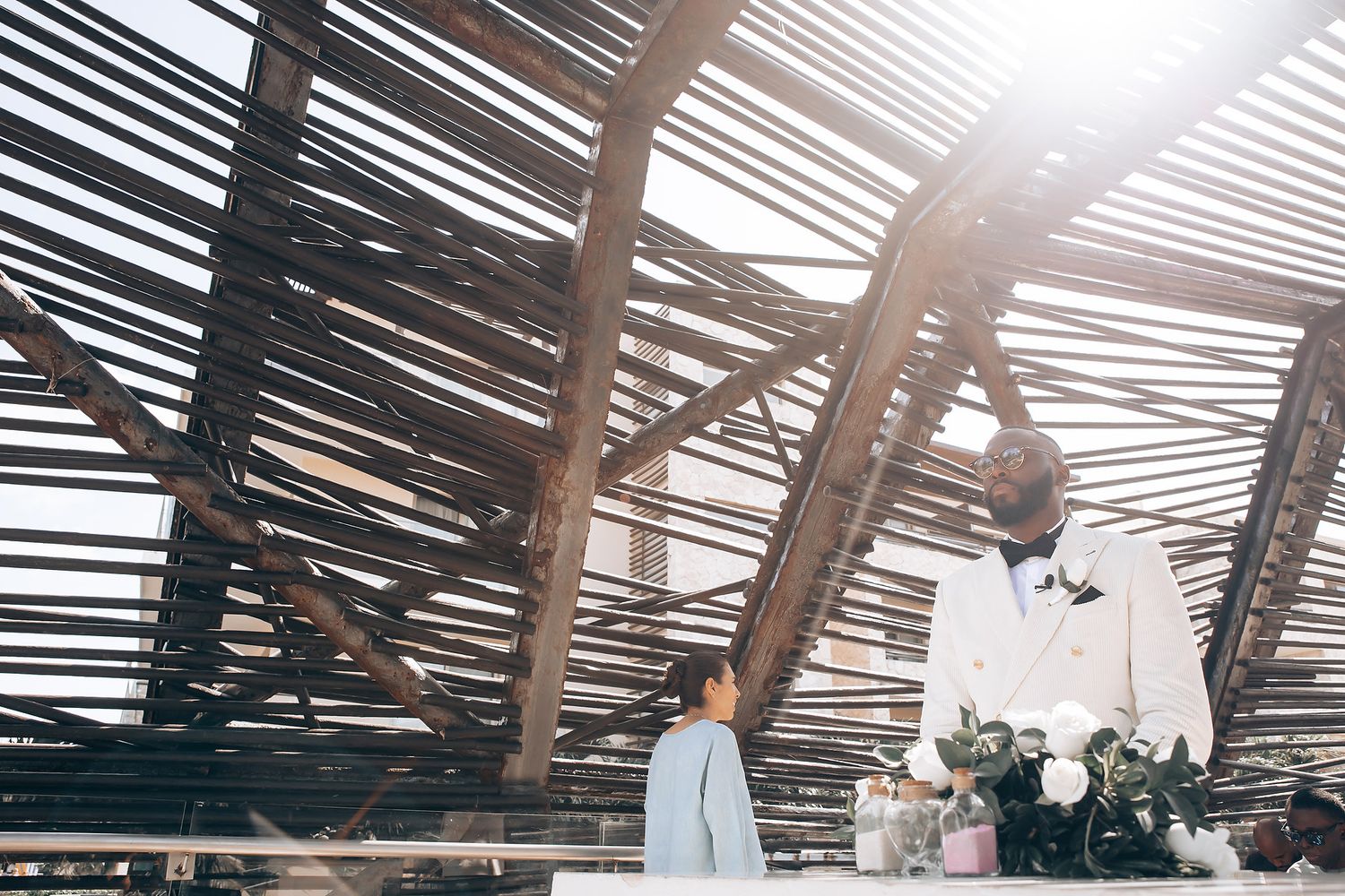 Natural light streams through wooden slats in a rustic venue ceiling creating dramatic shadows and patterns.