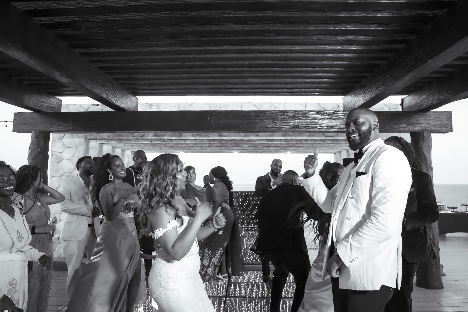 Wedding guests celebrate under a covered outdoor venue with white decor.