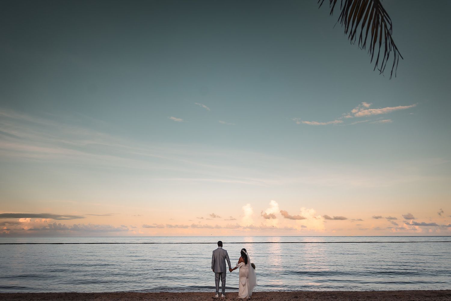 Panoramic beach sunset with silhouettes and ocean waves.