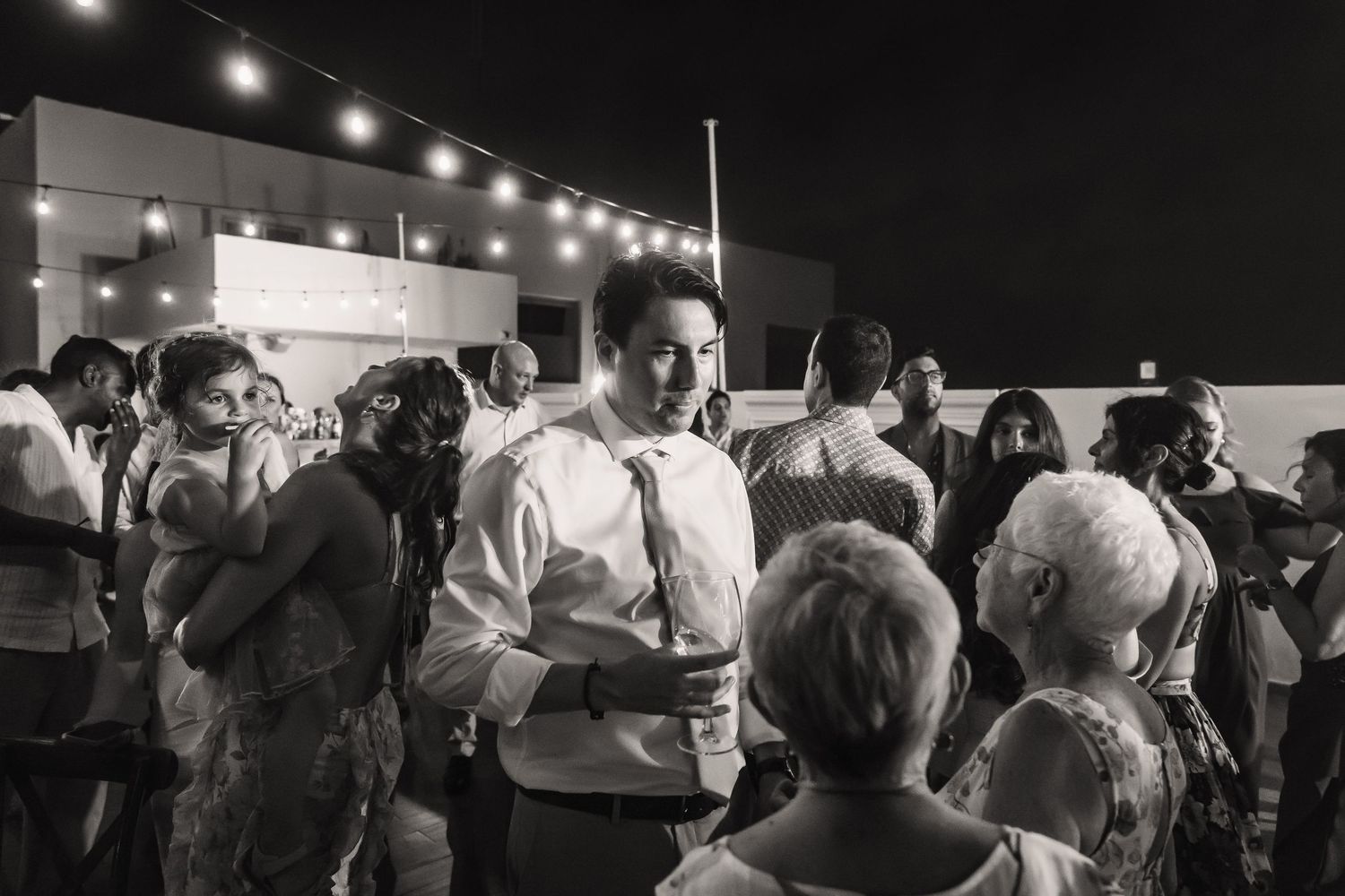 Wedding guests gathered on dance floor during evening reception.