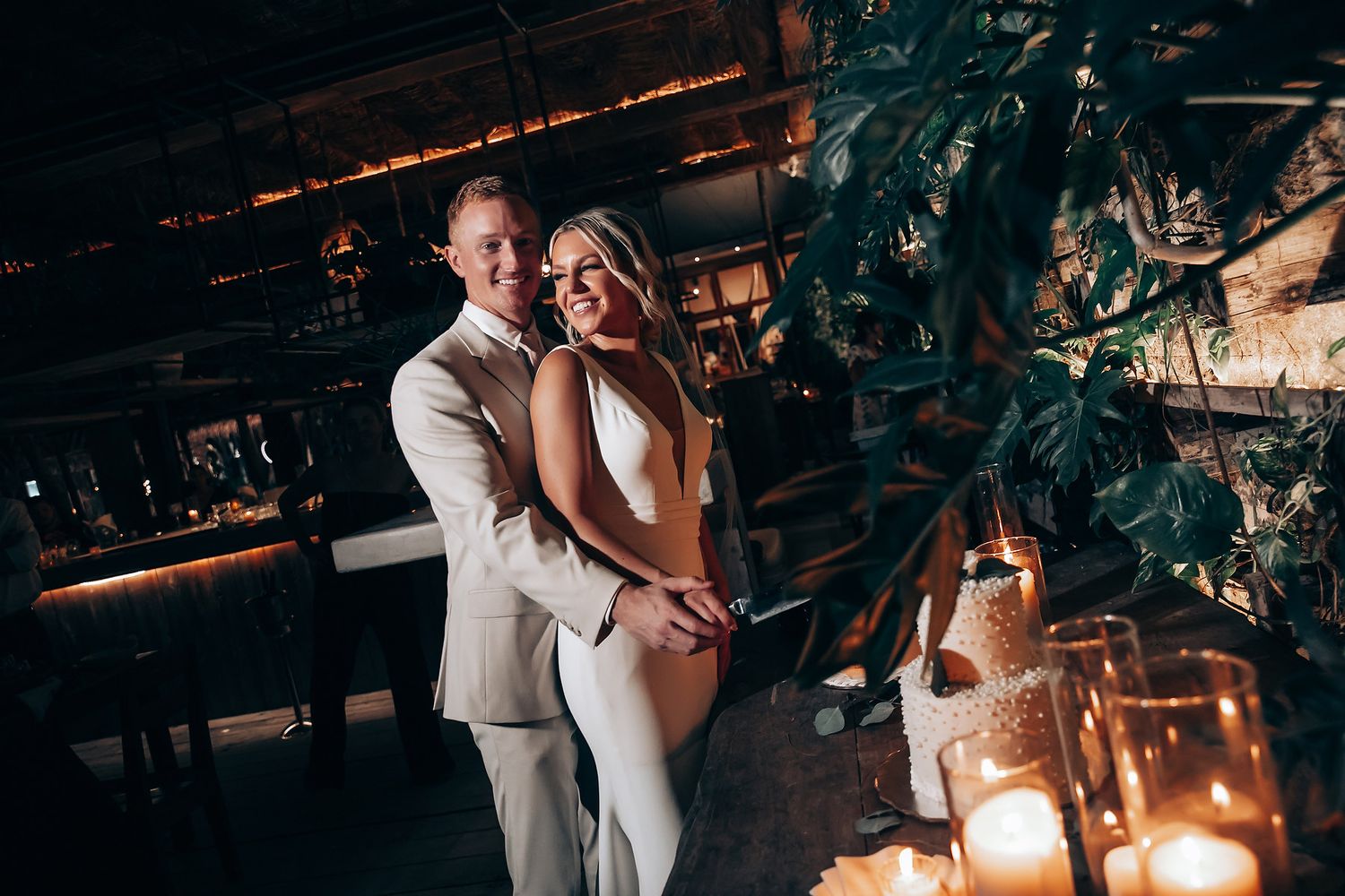 An intimate moment captured in a rustic venue with ambient candlelight and hanging plants.