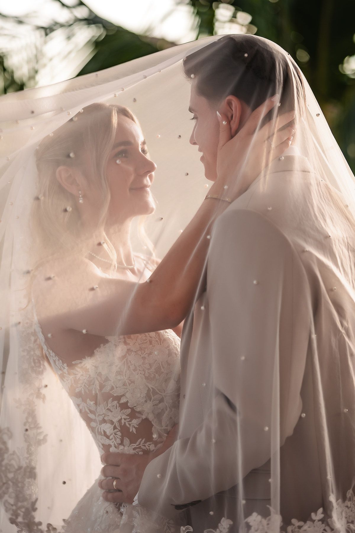 Romantic wedding moment captured through delicate veil in soft natural light.