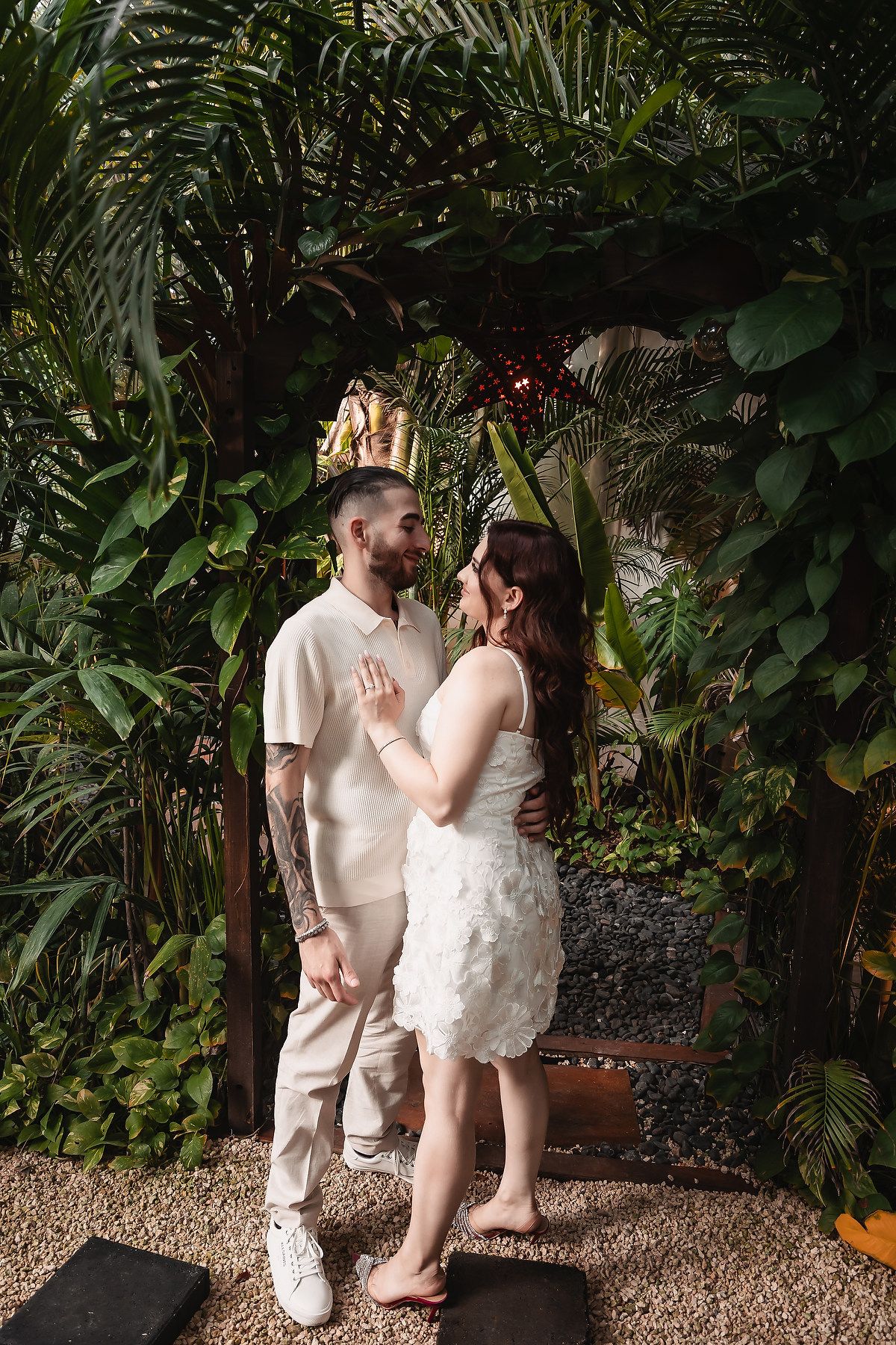 Romantic moment in a lush tropical garden setting with palm fronds and greenery.